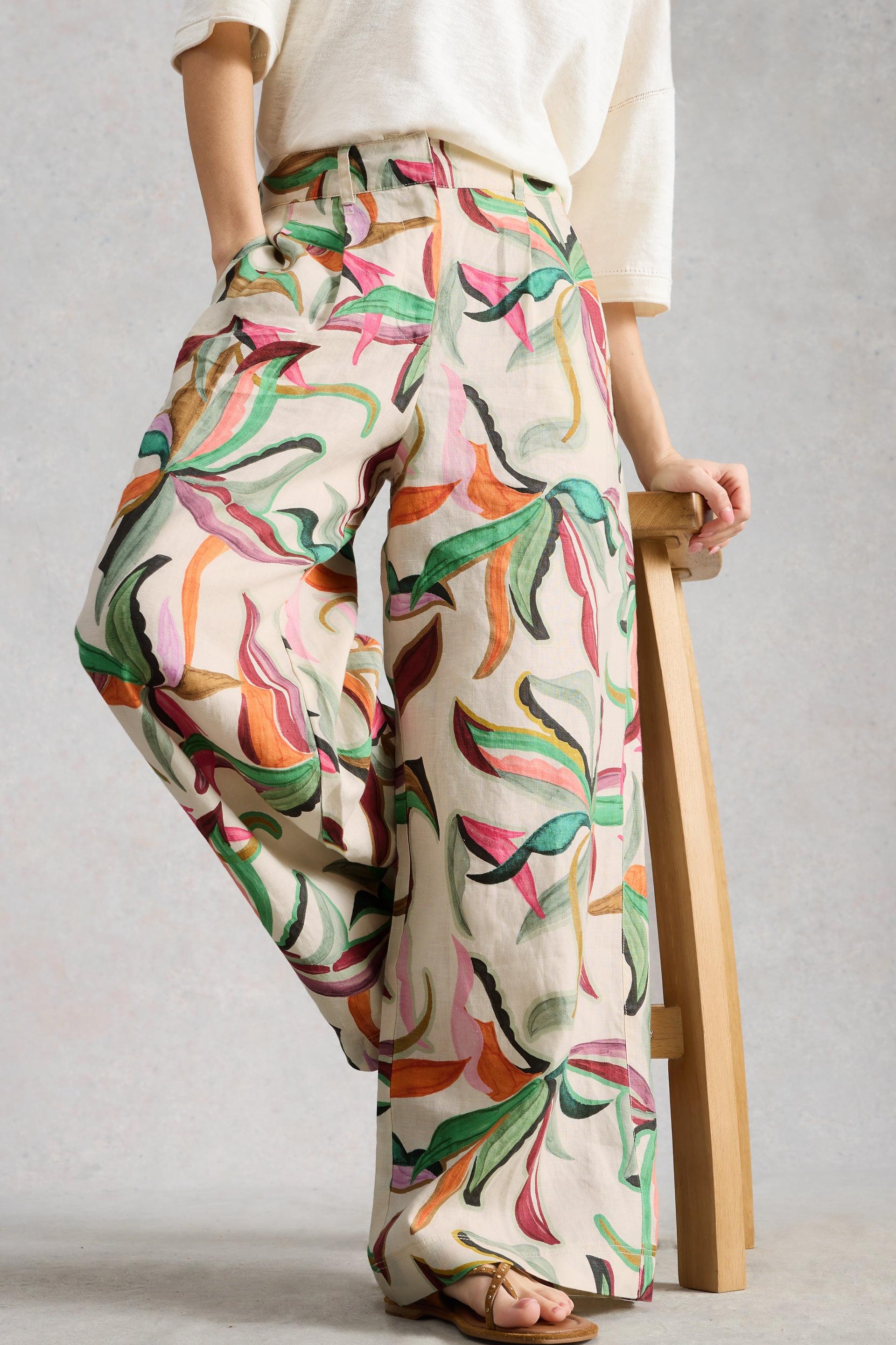 Person wearing colorful wide leg linen trousers with a plain background