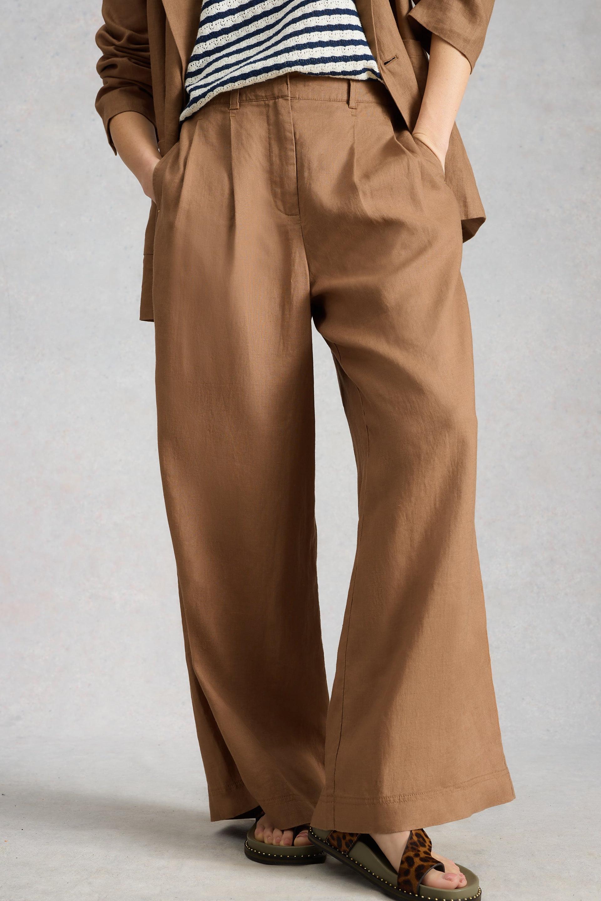 Person wearing brown wide-leg pants with a neutral background
