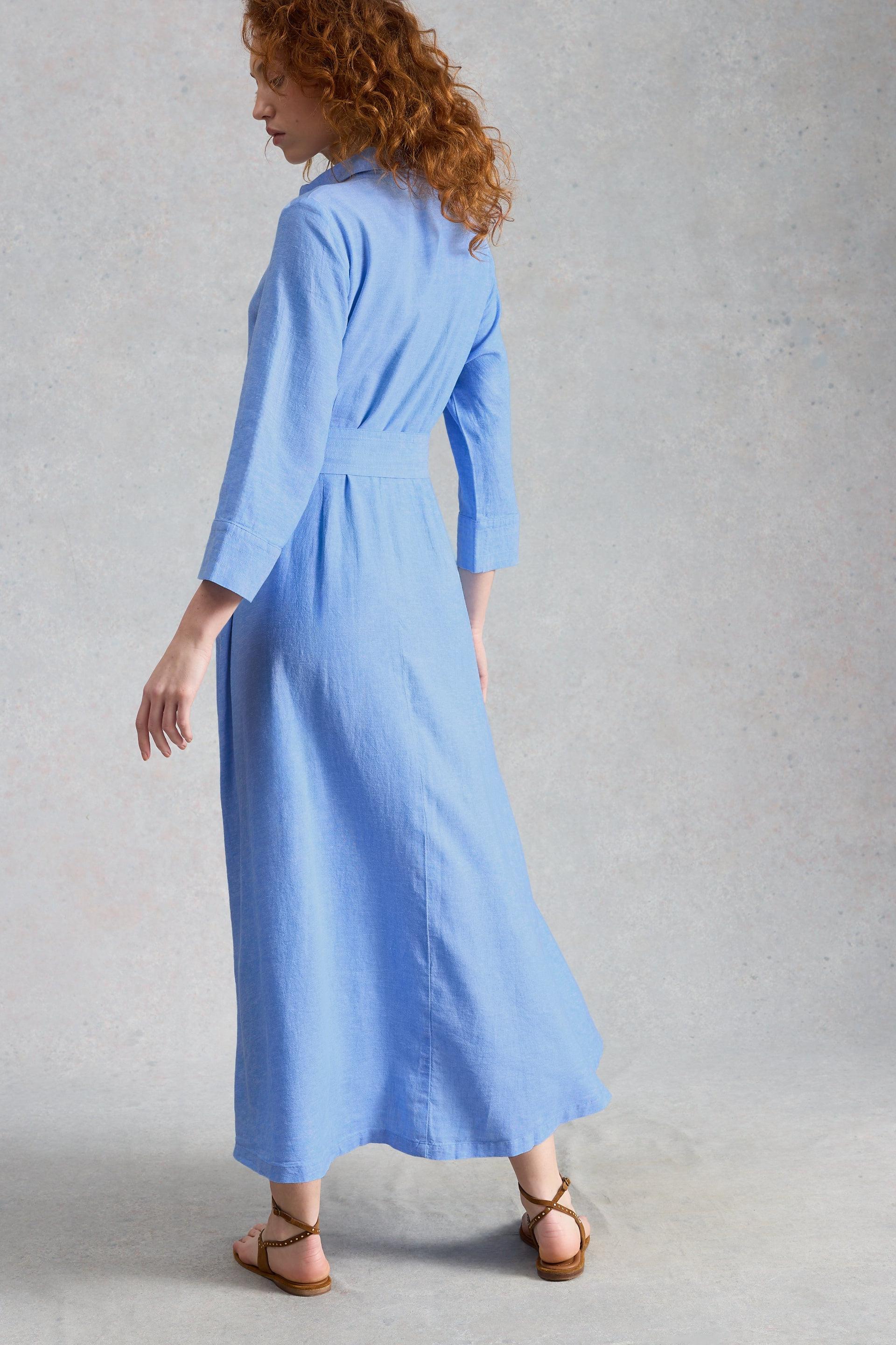 Woman wearing a light blue shirt dress against a plain background