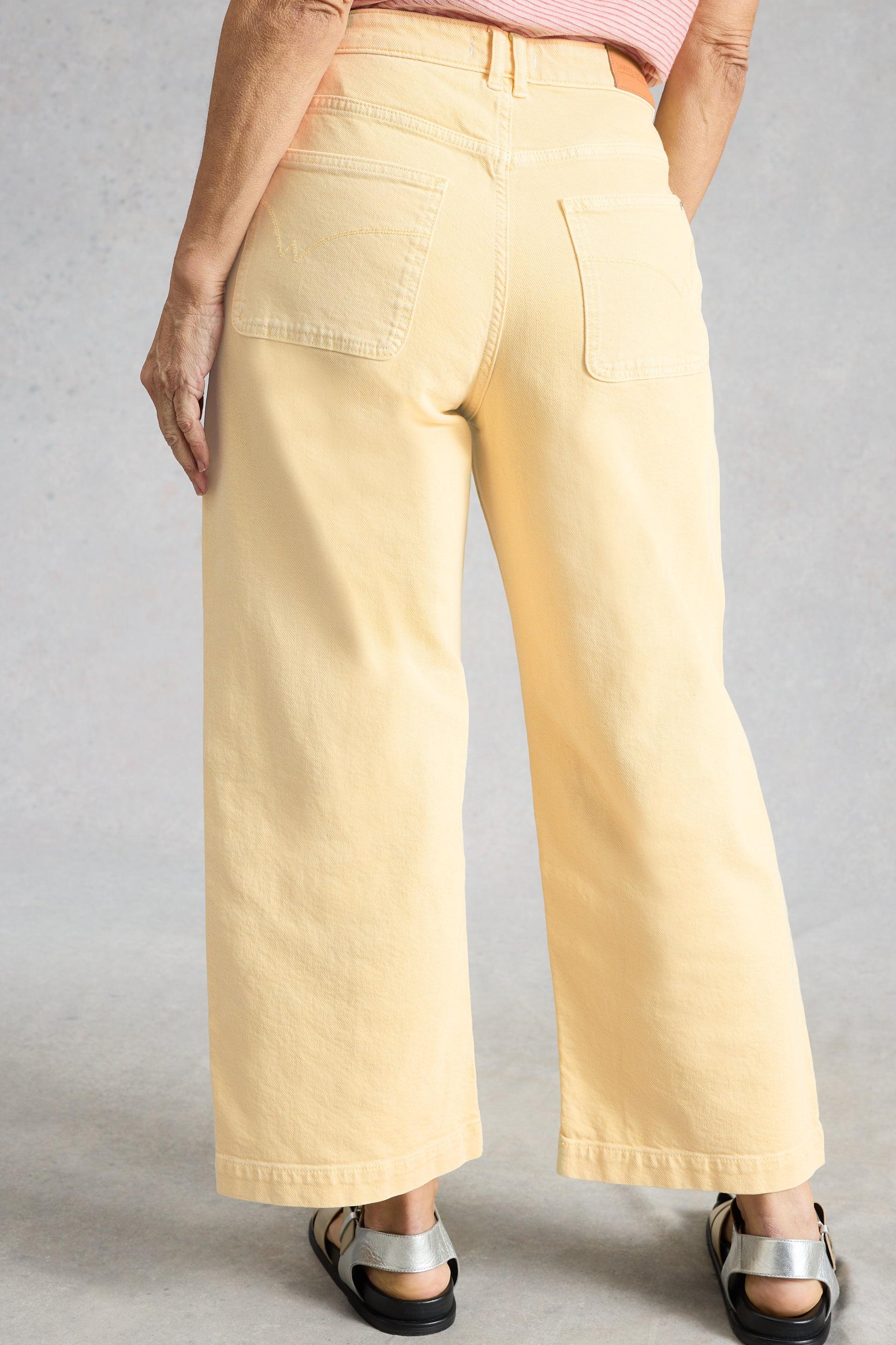 Woman wearing light yellow wide-leg pants on a plain background