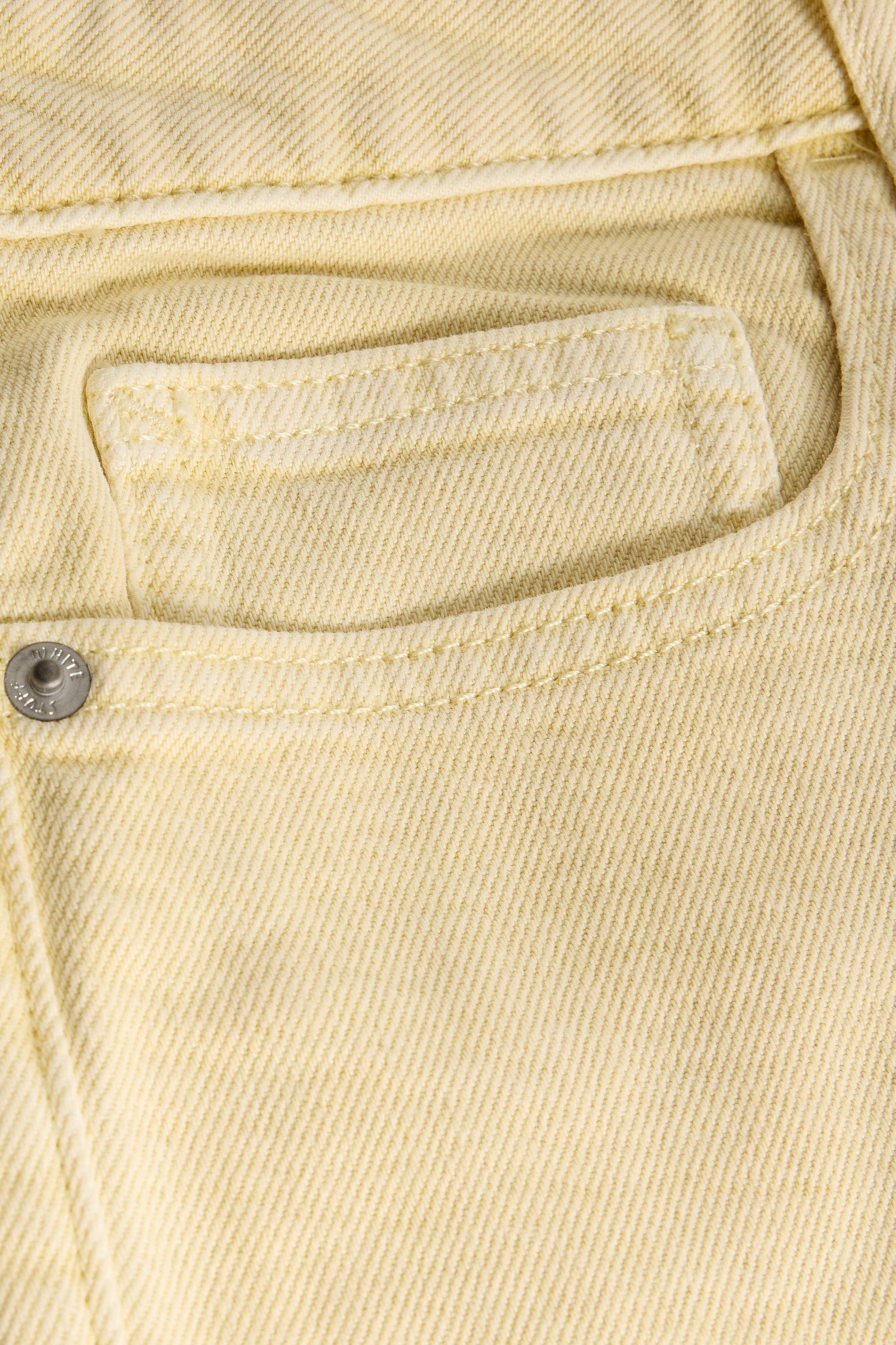 Close-up of yellow denim fabric with a button