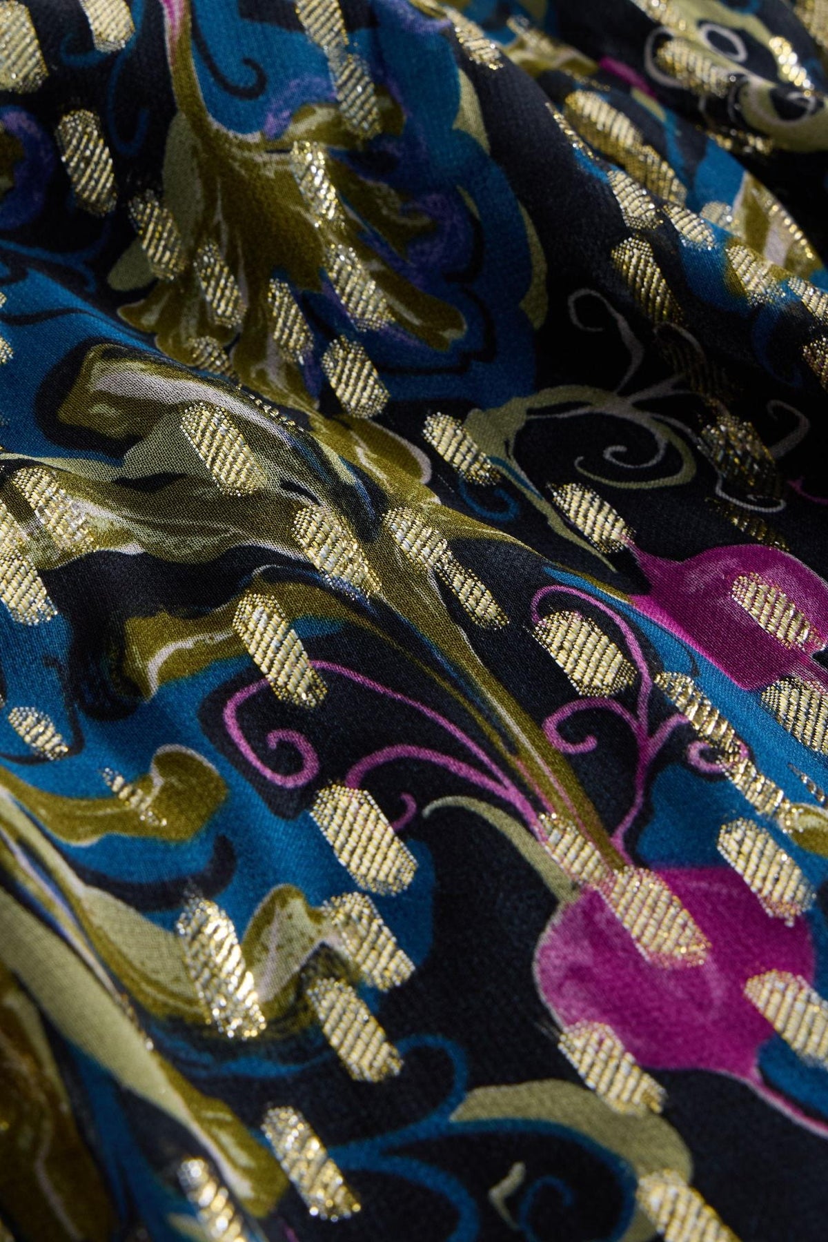 Close-up of a White Stuff viscose dress featuring a vibrant floral pattern with gold metallic thread accents.