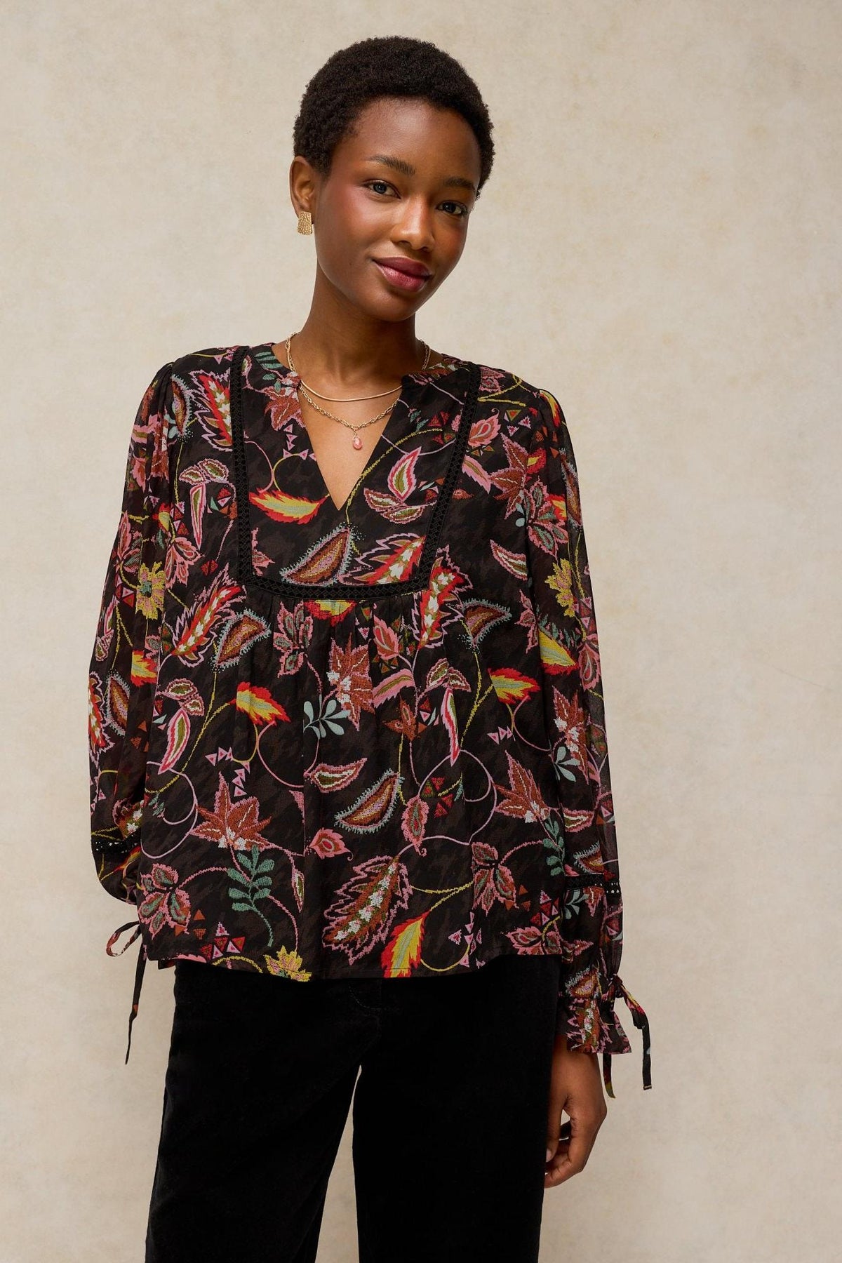 Woman wearing a black long-sleeve White Stuff viscose shirt with a vibrant paisley pattern.