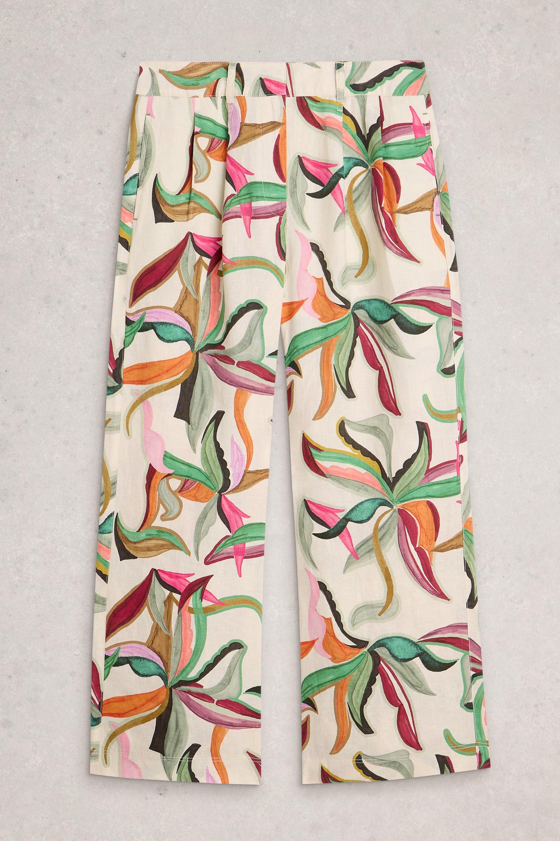 Colourful floral-patterned linen pants on a gray background