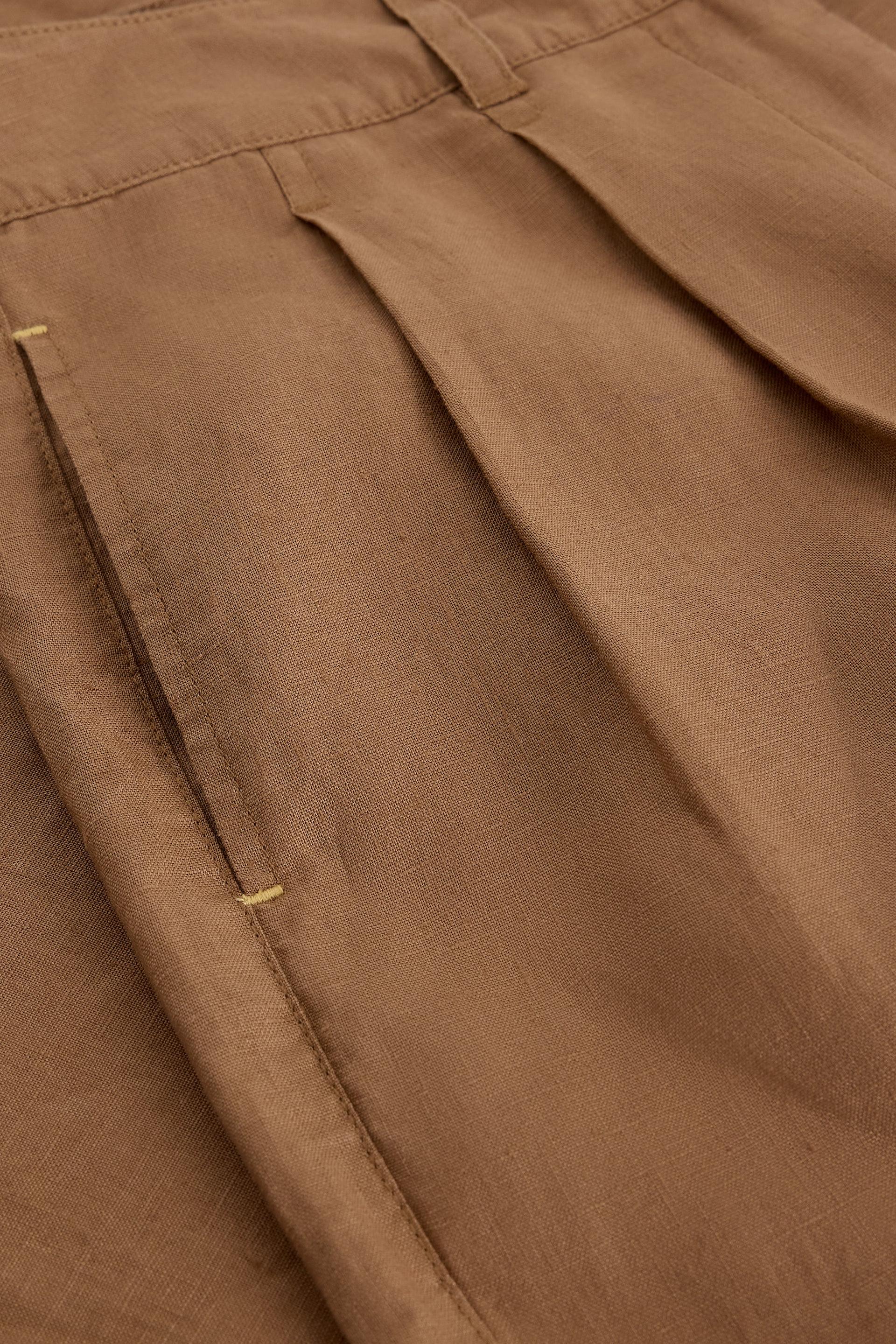 Close-up of brown linen pants with a focus on texture and stitching detail.
