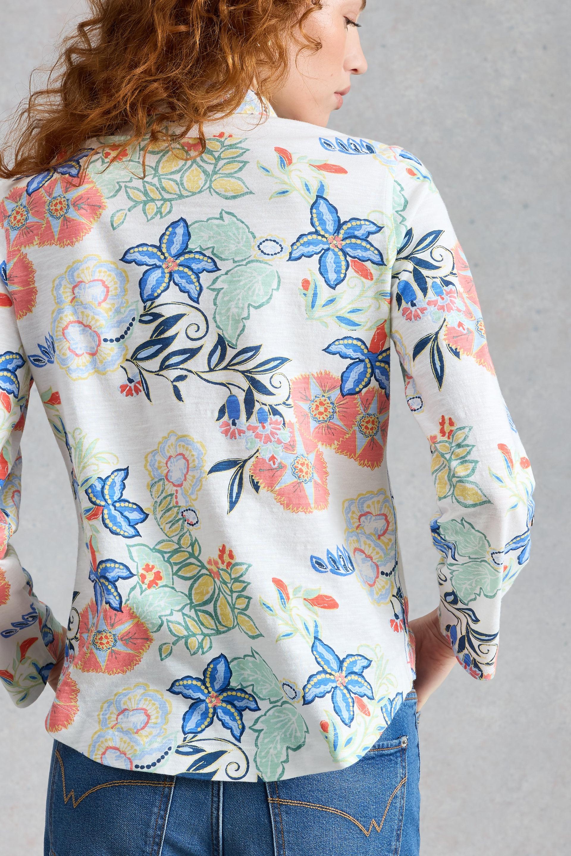 Woman wearing a colourful floral cotton blouse against a gray background