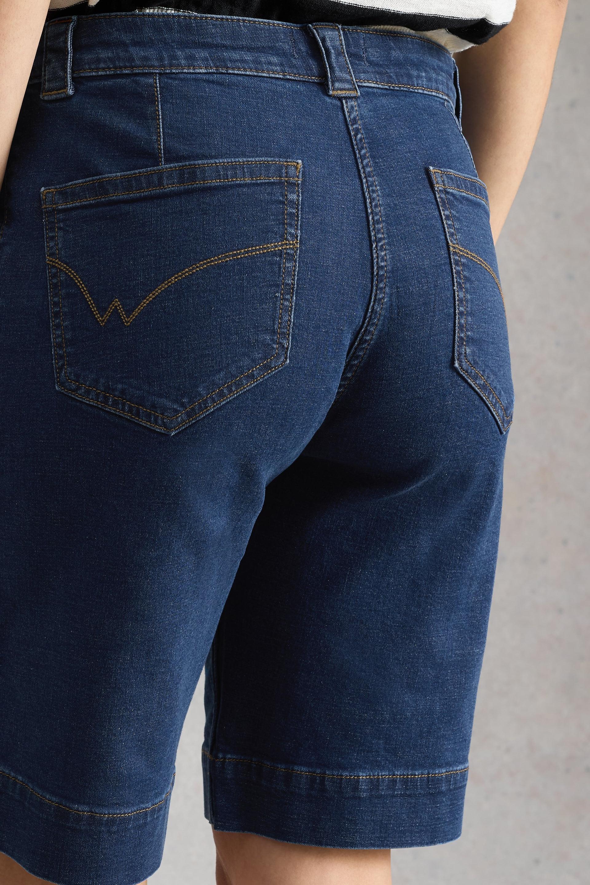 Blue denim shorts with White Stuff stitching on back pockets on a plain background