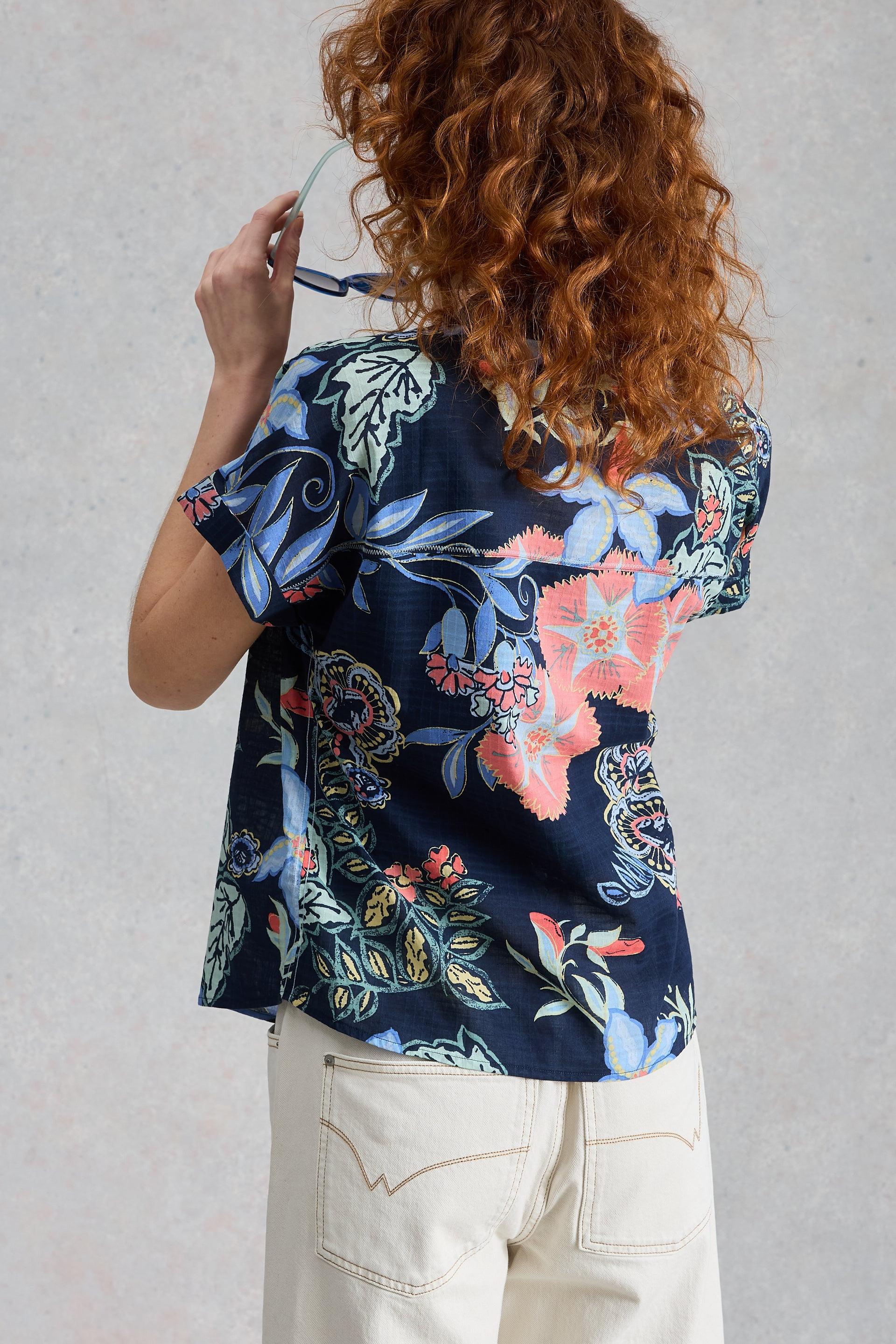 Person wearing a floral organic cotton blouse with a neutral background
