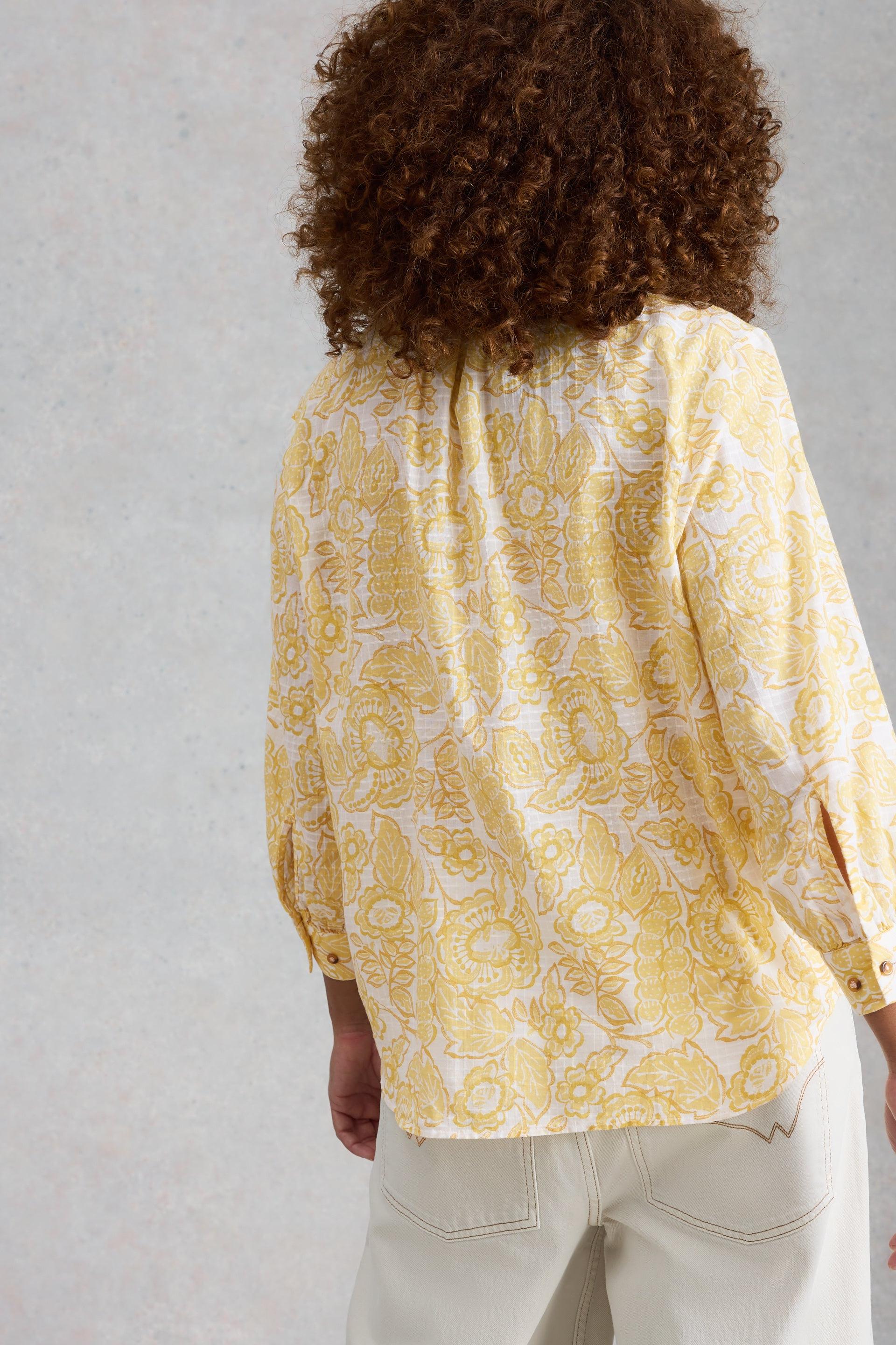 Person wearing a yellow organic cotton shirt against a plain background