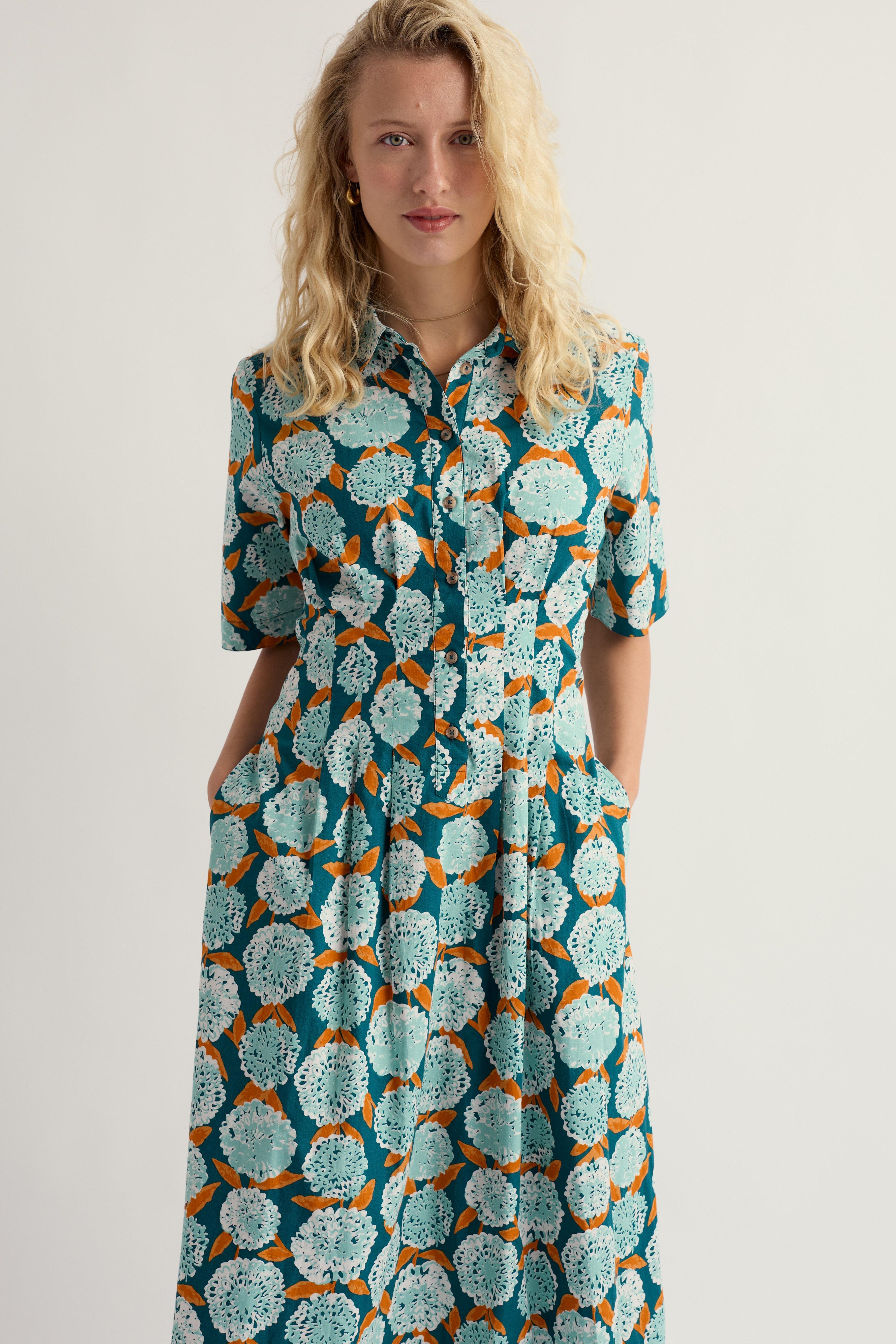 Woman wearing a patterned Seasalt dress on a plain background