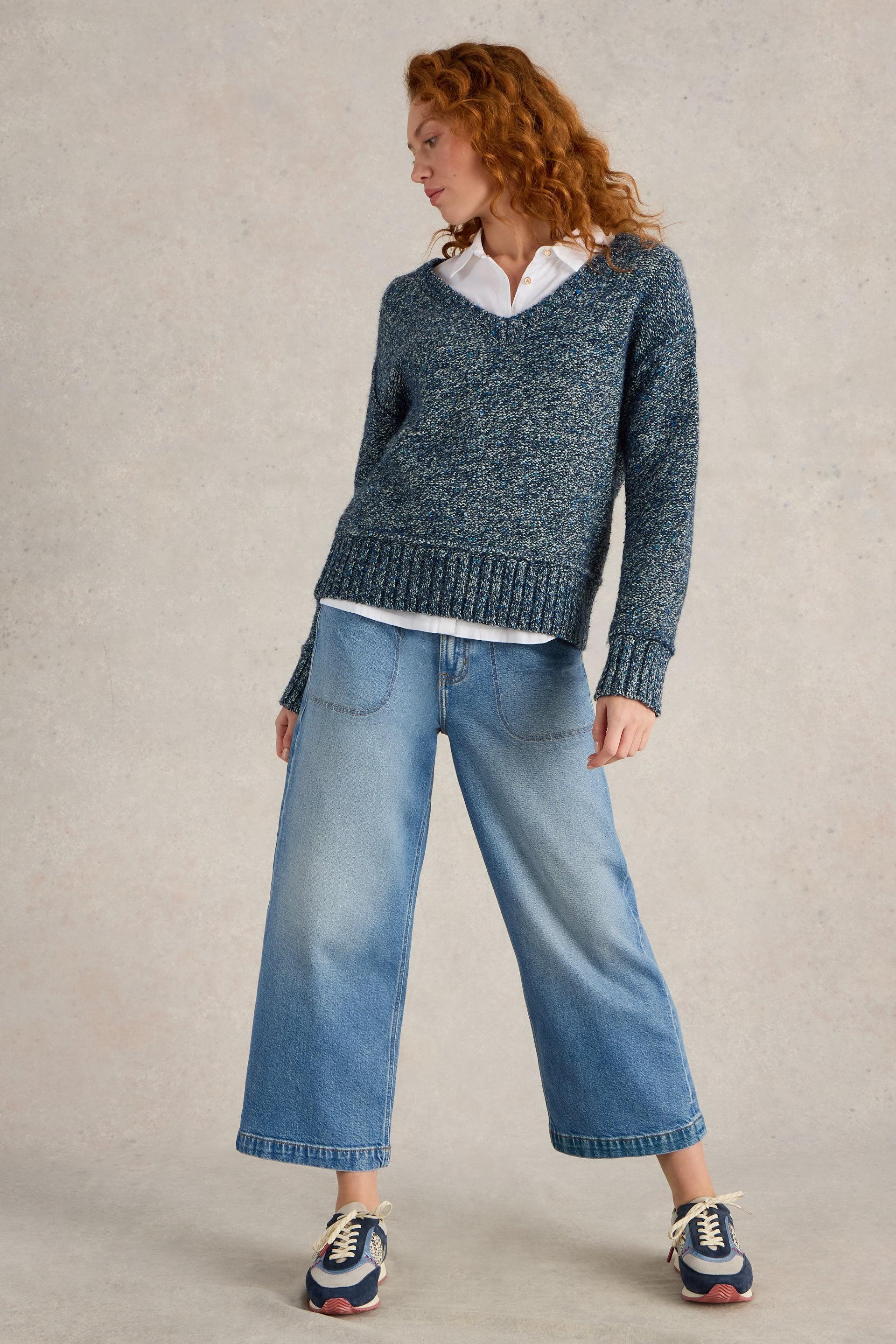 Woman wearing a textured blue sweater over a crisp organic cotton white shirt and wide-leg jeans