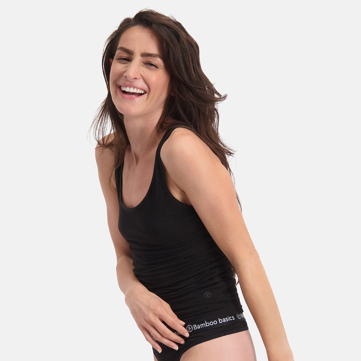 A smiling woman wearing a soft black bamboo fabric tank top and matching underwear.
