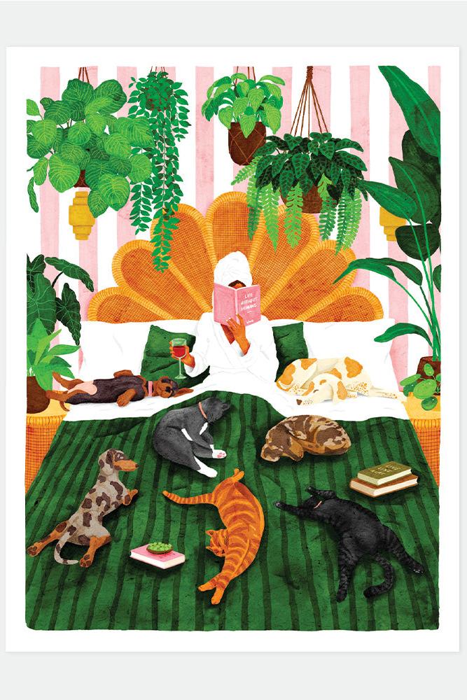 A woman in a robe and towel reading a book in bed surrounded by several dogs, cats, and hanging plants.