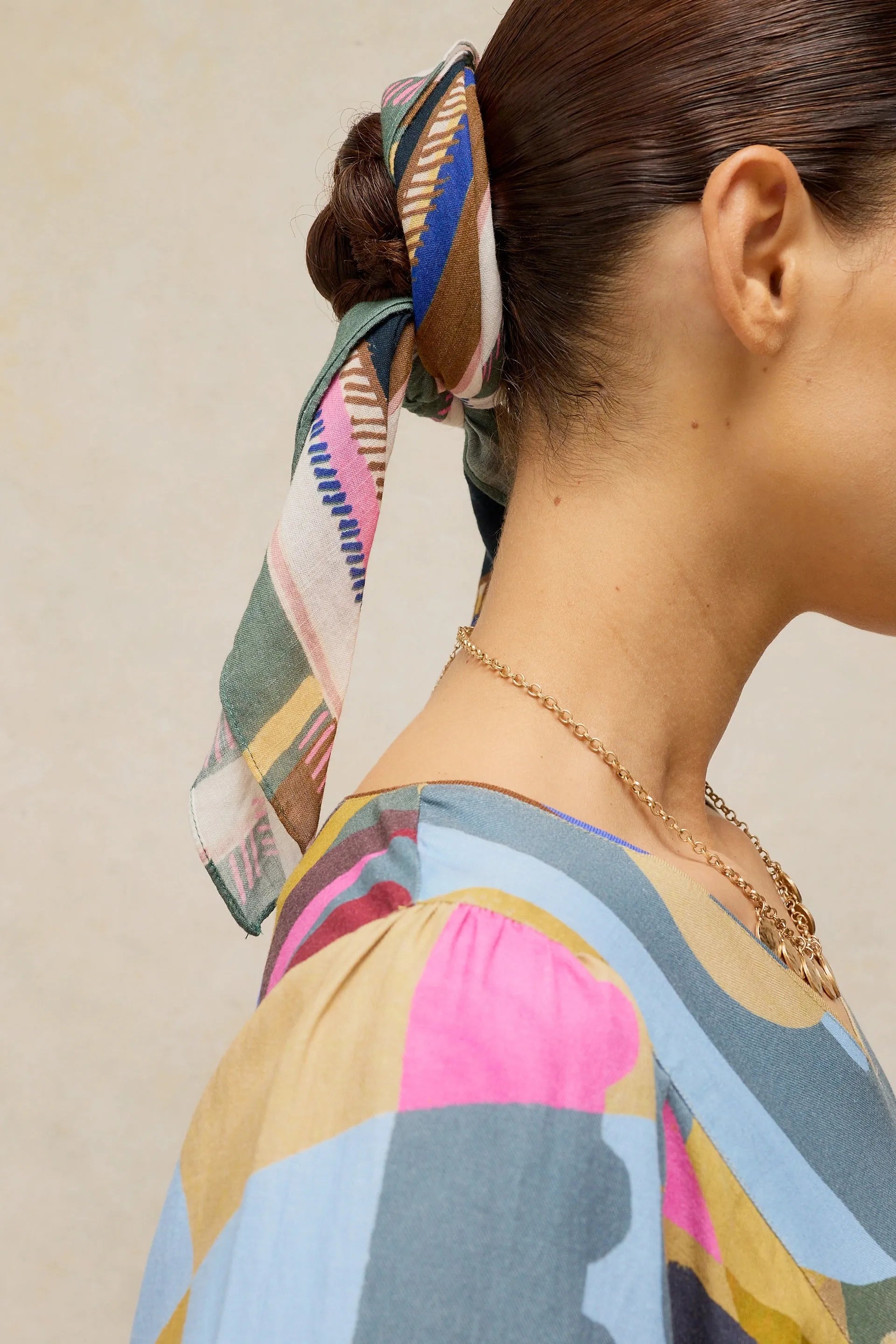 Profile view of a woman with a colorful patterned headscarf tied around her hair bun