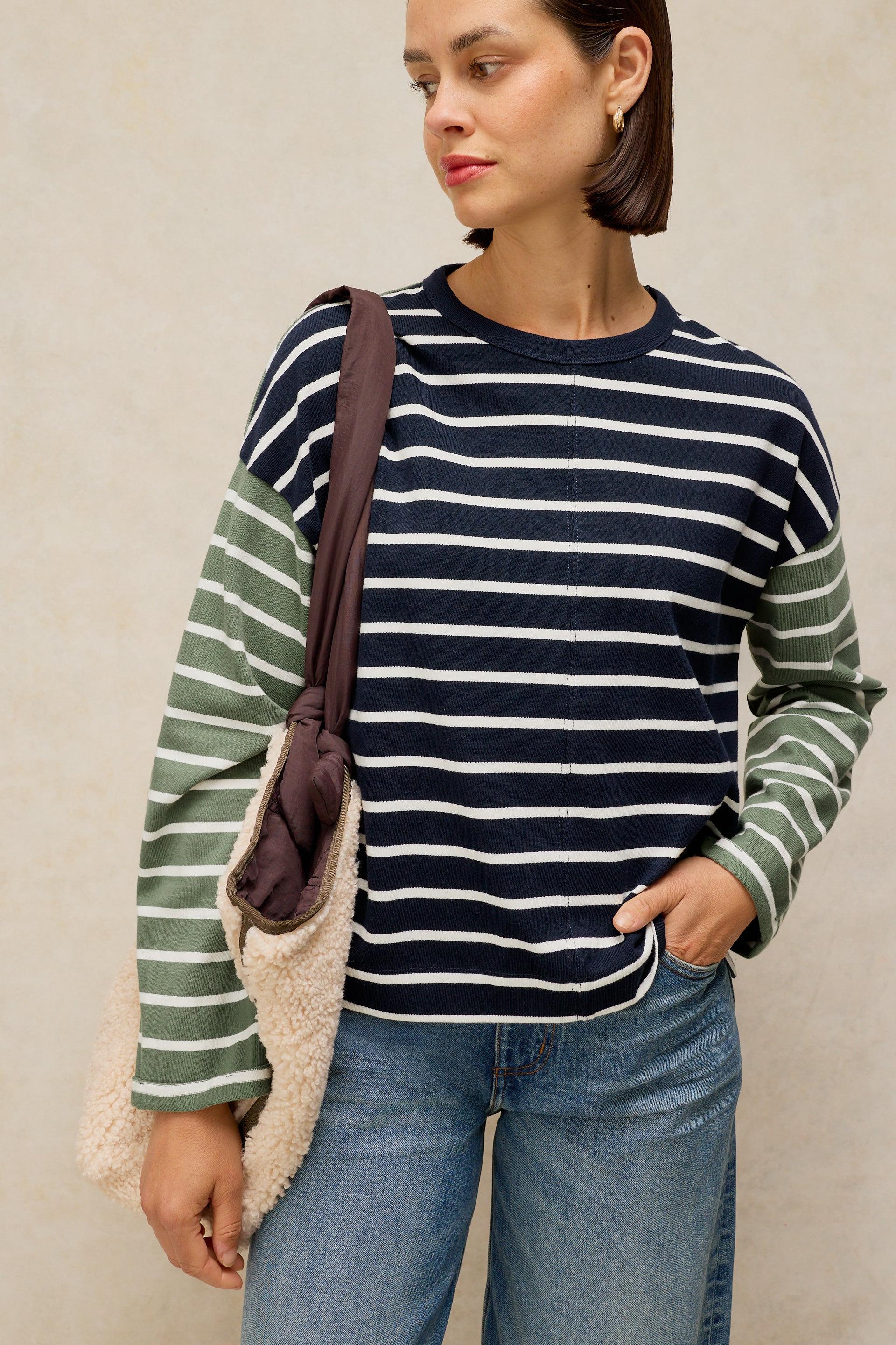 Woman wearing a navy and green striped organic cotton top carrying a textured white stuff bag