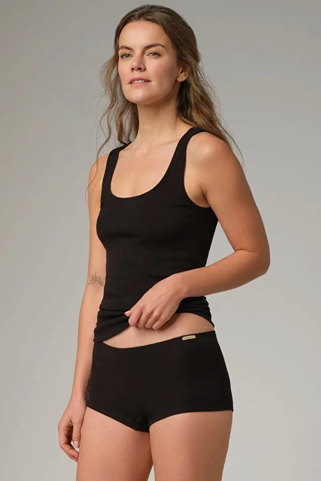 A woman wearing a black Comazo organic cotton tank top and matching briefs against a neutral studio background.