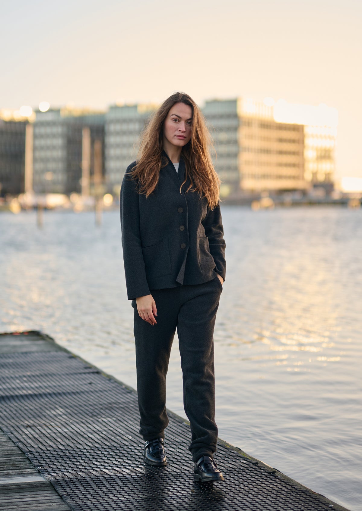 Woman wearing a black Henriette Steffensen fleece cardigan outdoors by the water.
