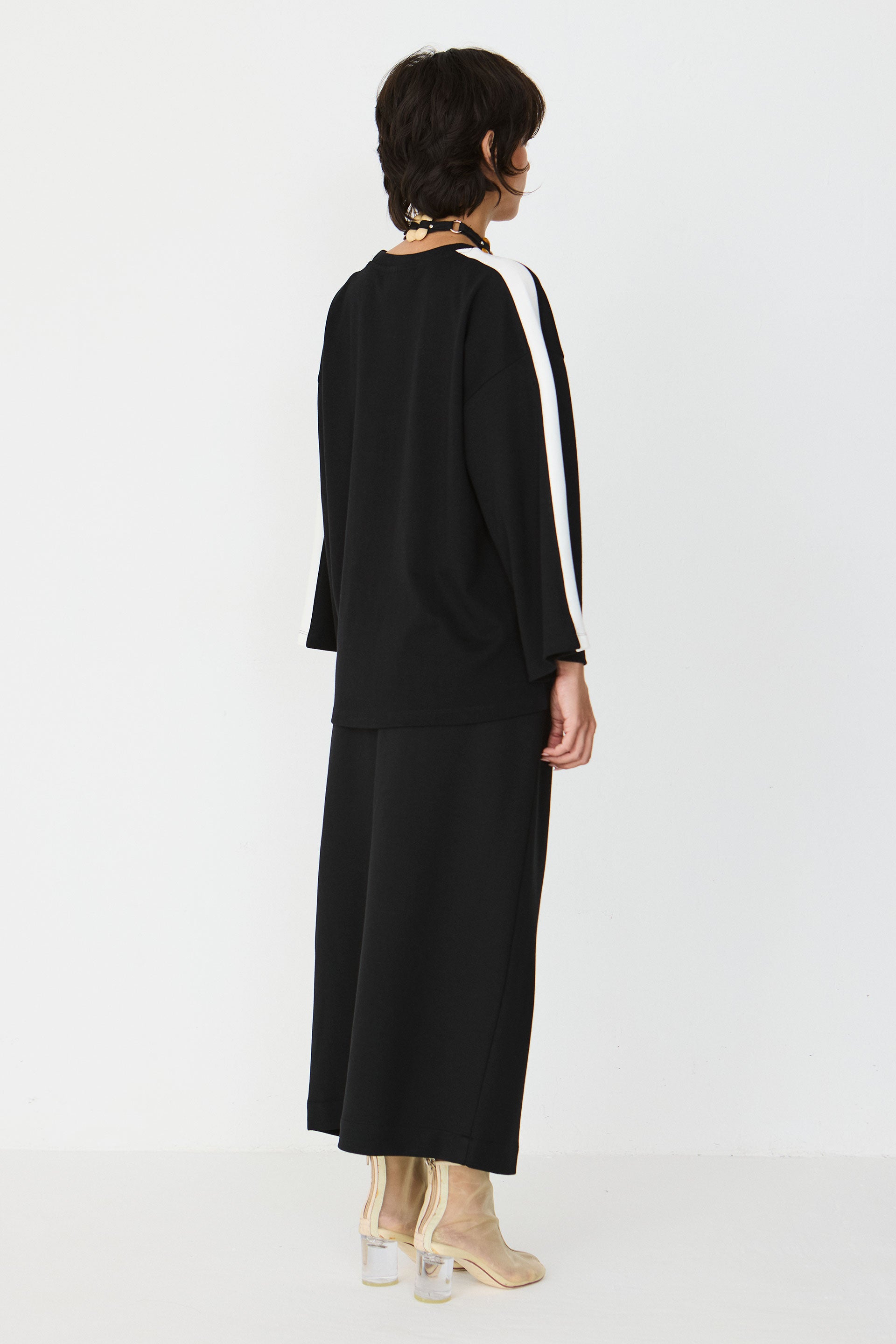 Person wearing a black organic cotton outfit with white stripes on a white background