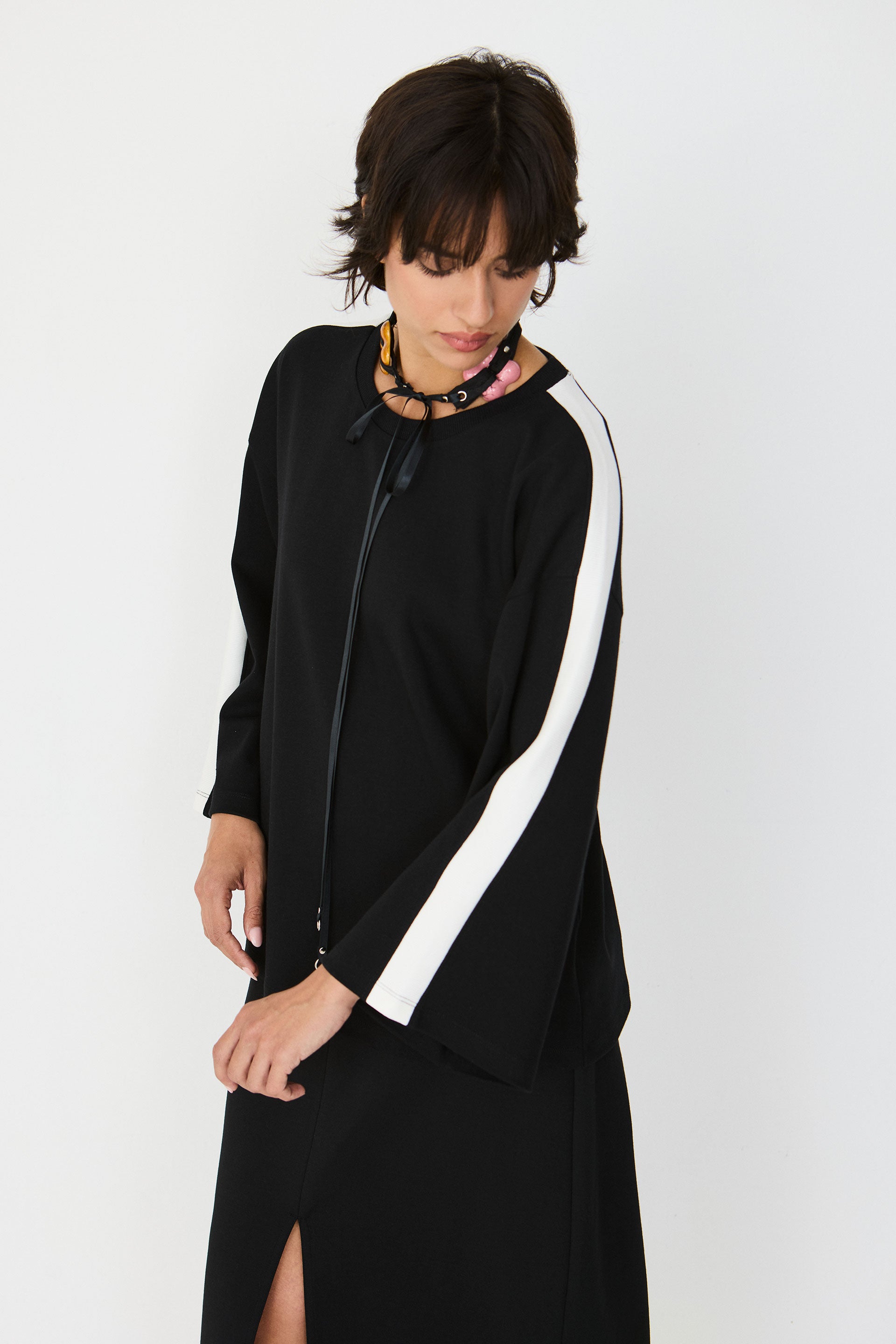 Person wearing a black co-ord with a white stripe on a white background