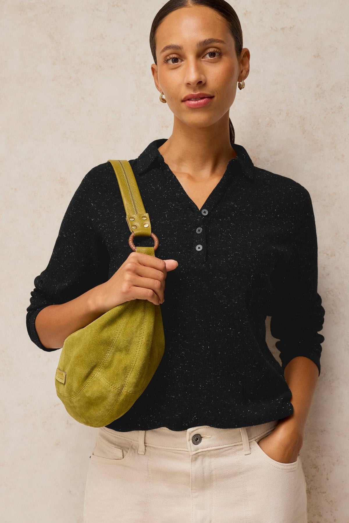 A woman modeling a black rib cotton polo sparkle top with a green suede shoulder bag.