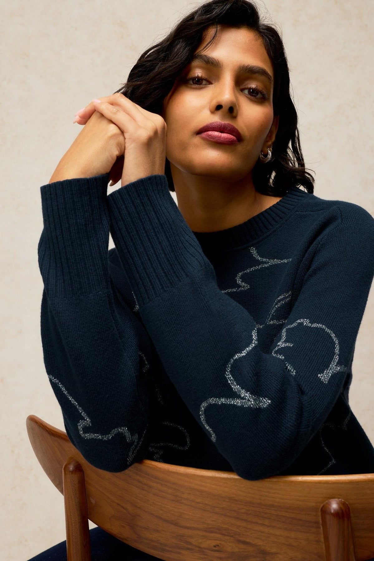A woman wearing a black sparkly women's knit jumper with silver abstract line designs.