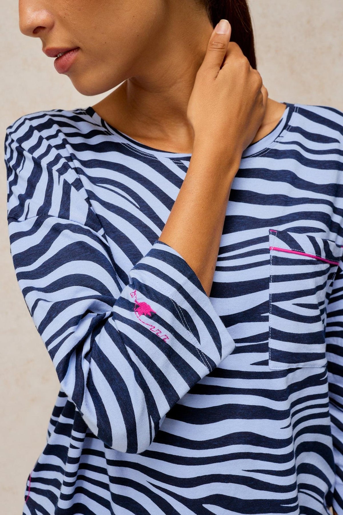 A woman wearing a blue animal print White Stuff long-sleeve pyjama top with a chest pocket.
