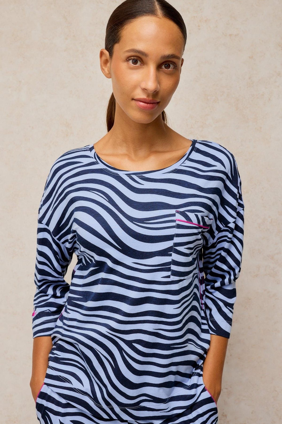 A woman wearing a blue zebra animal print White Stuff pyjama top with a pocket detail.