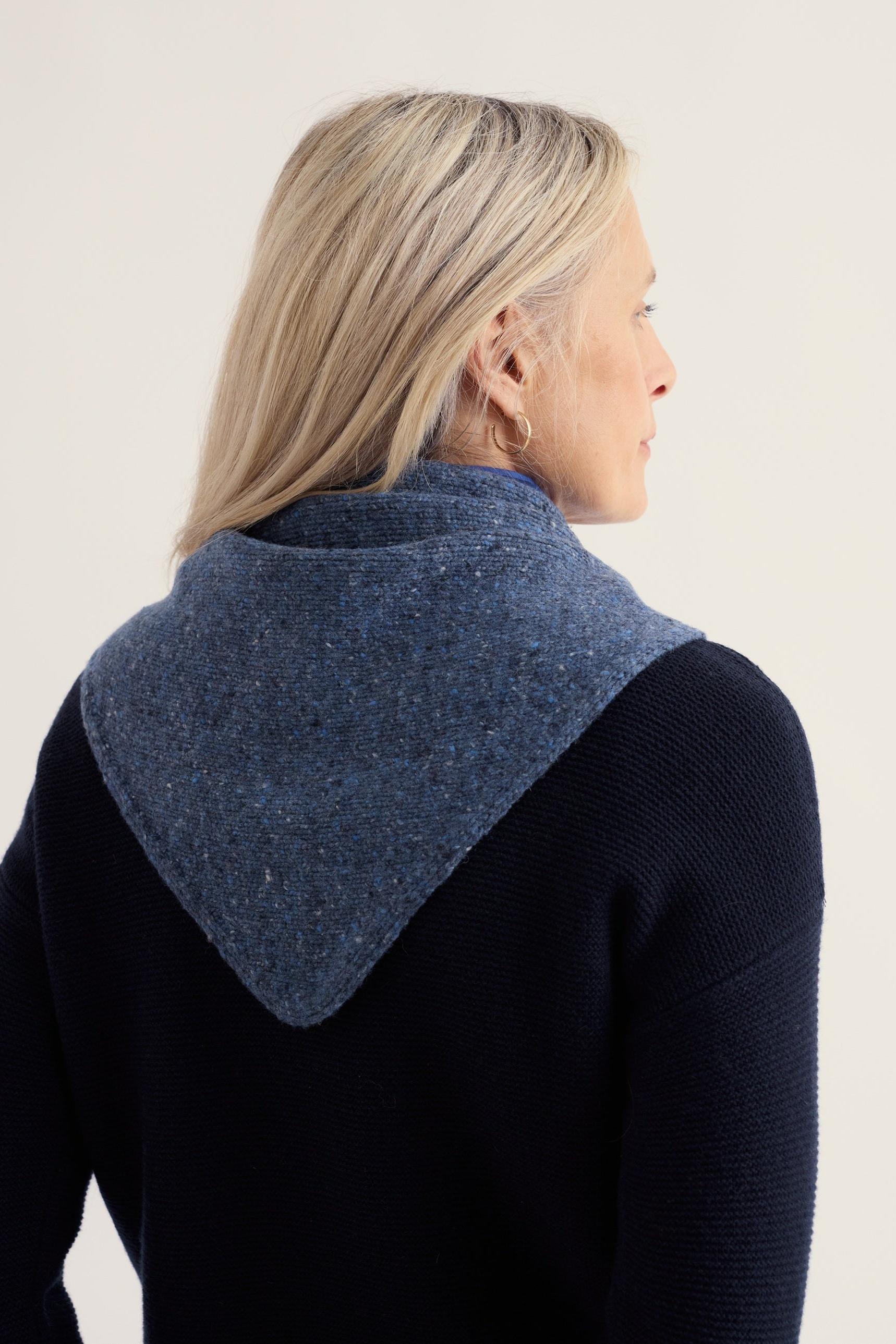 A woman wearing a blue speckled knit scarf from Seasalt Cornwall over a dark navy sweater.