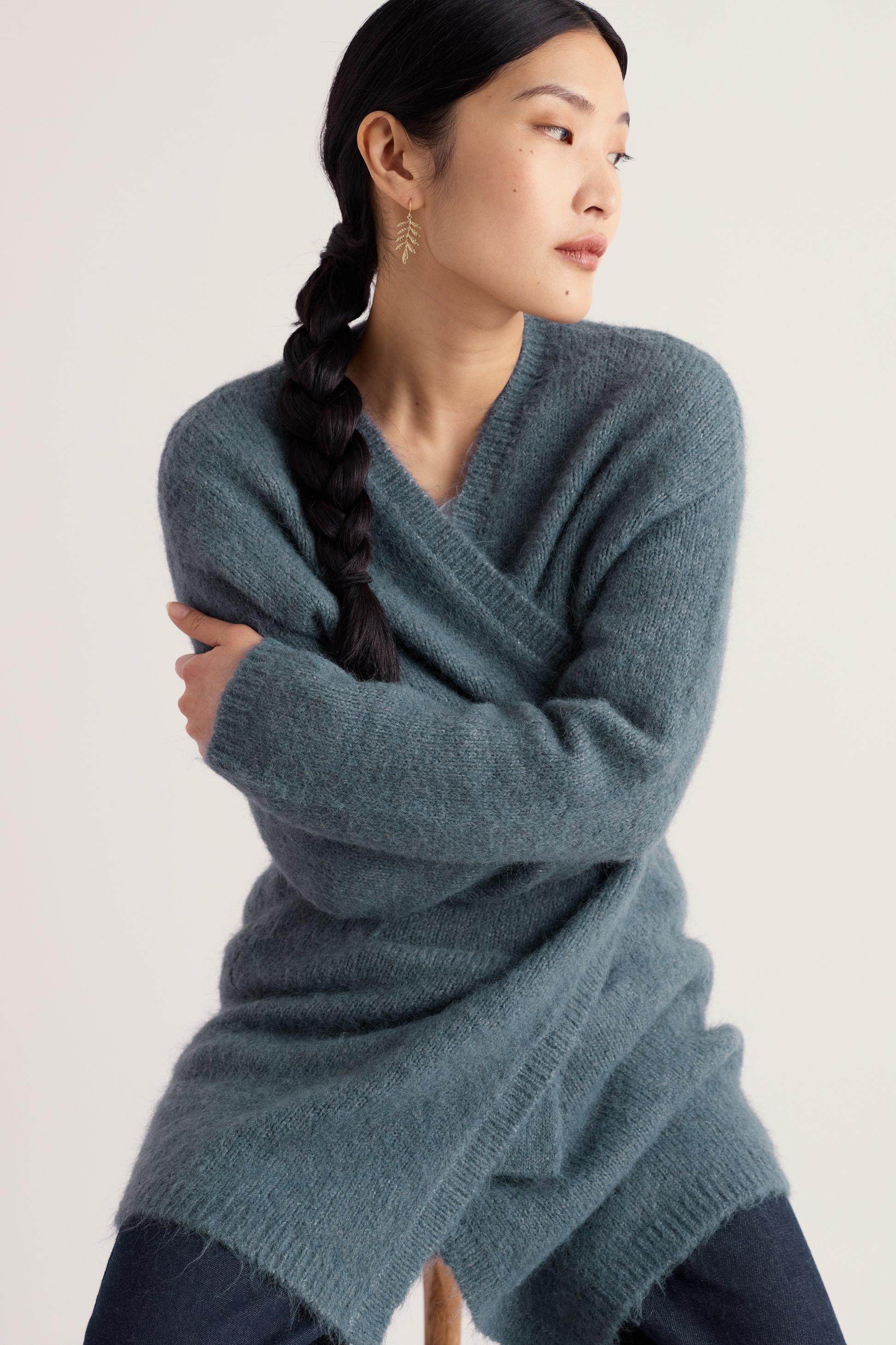 A woman wearing a soft blue Seasalt Cornwall mohair long cardigan against a plain background.