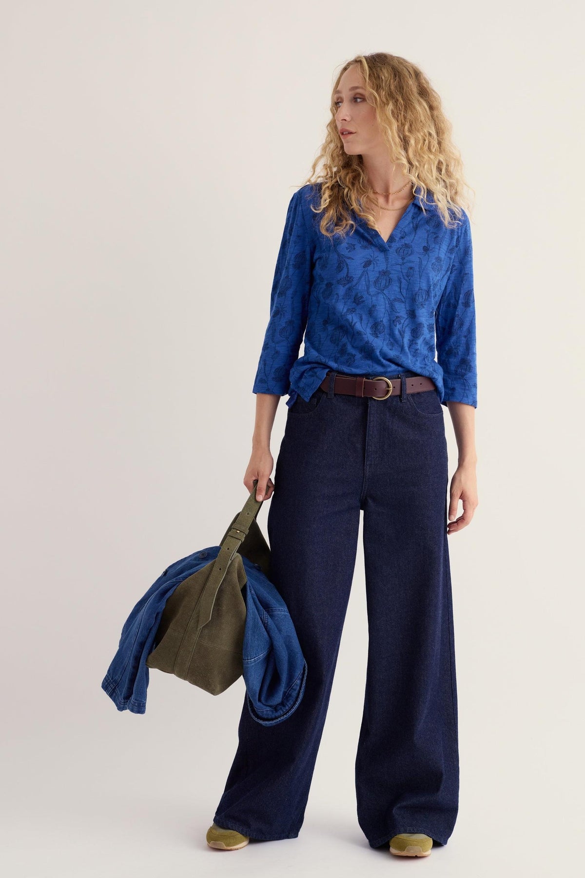 Woman wearing a patterned blue Seasalt organic cotton shirt with wide-leg dark jeans.