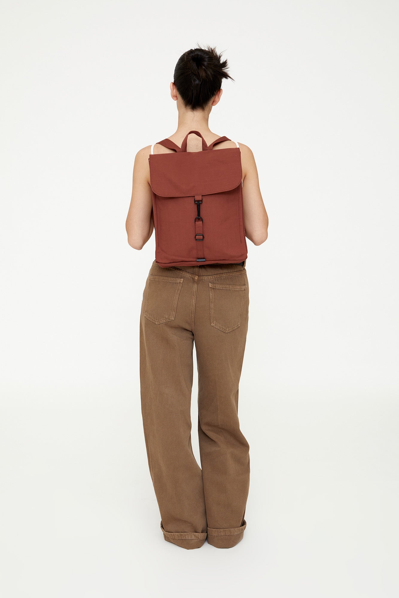 Person wearing a brown backpack and pants on a white background