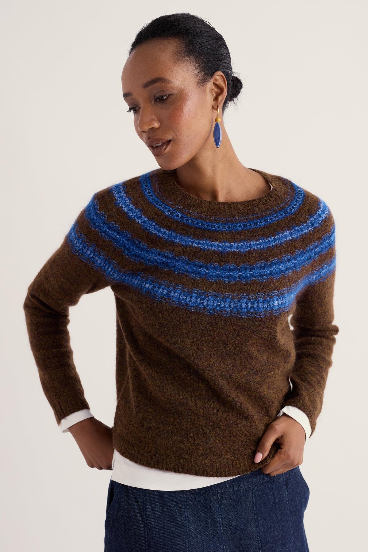 A woman wearing a brown and blue Fair Isle patterned wool jumper against a plain background.