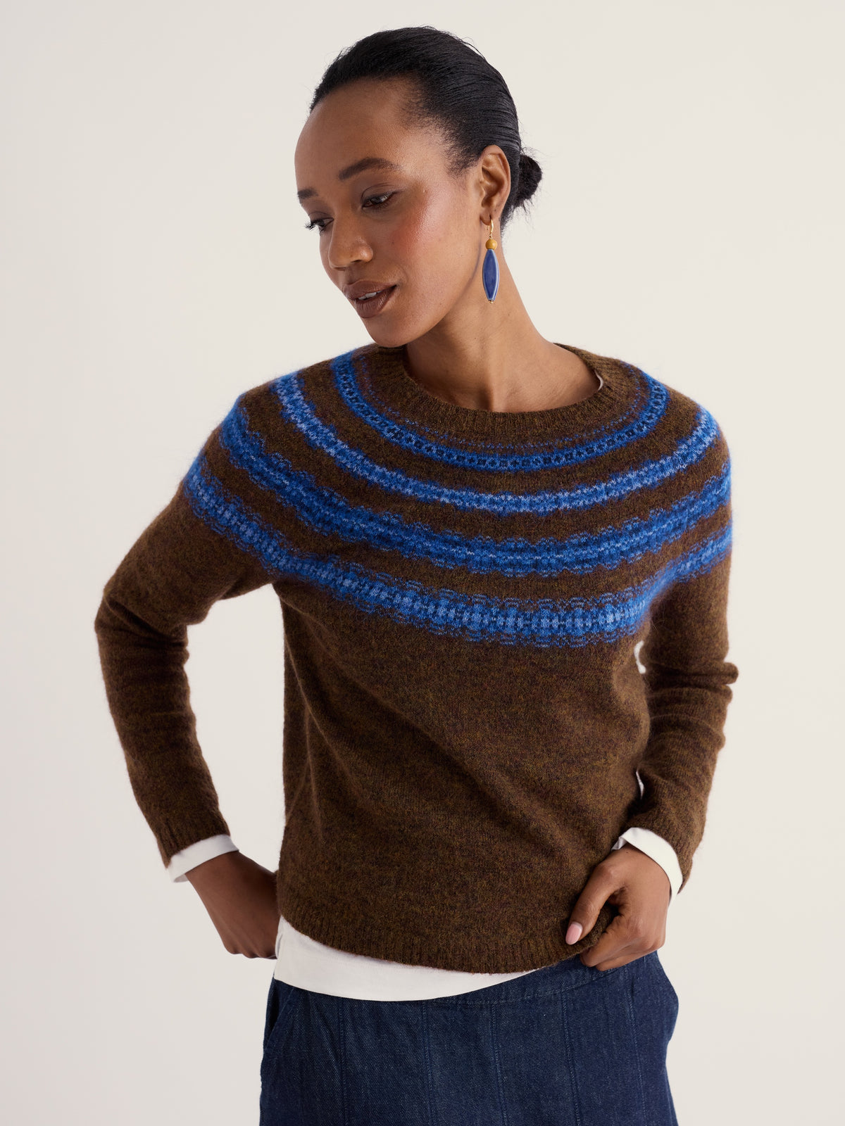 A woman wearing a brown and blue Fair Isle patterned wool jumper against a plain background.