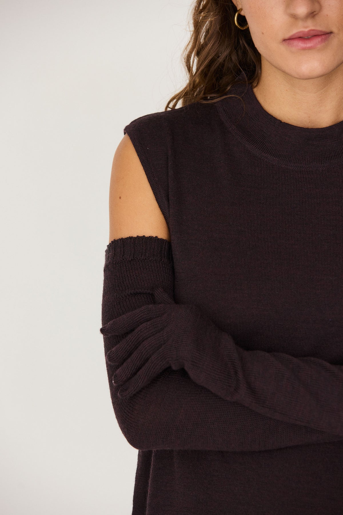 Woman posing in a dark brown sleeveless top with matching full length wool gloves