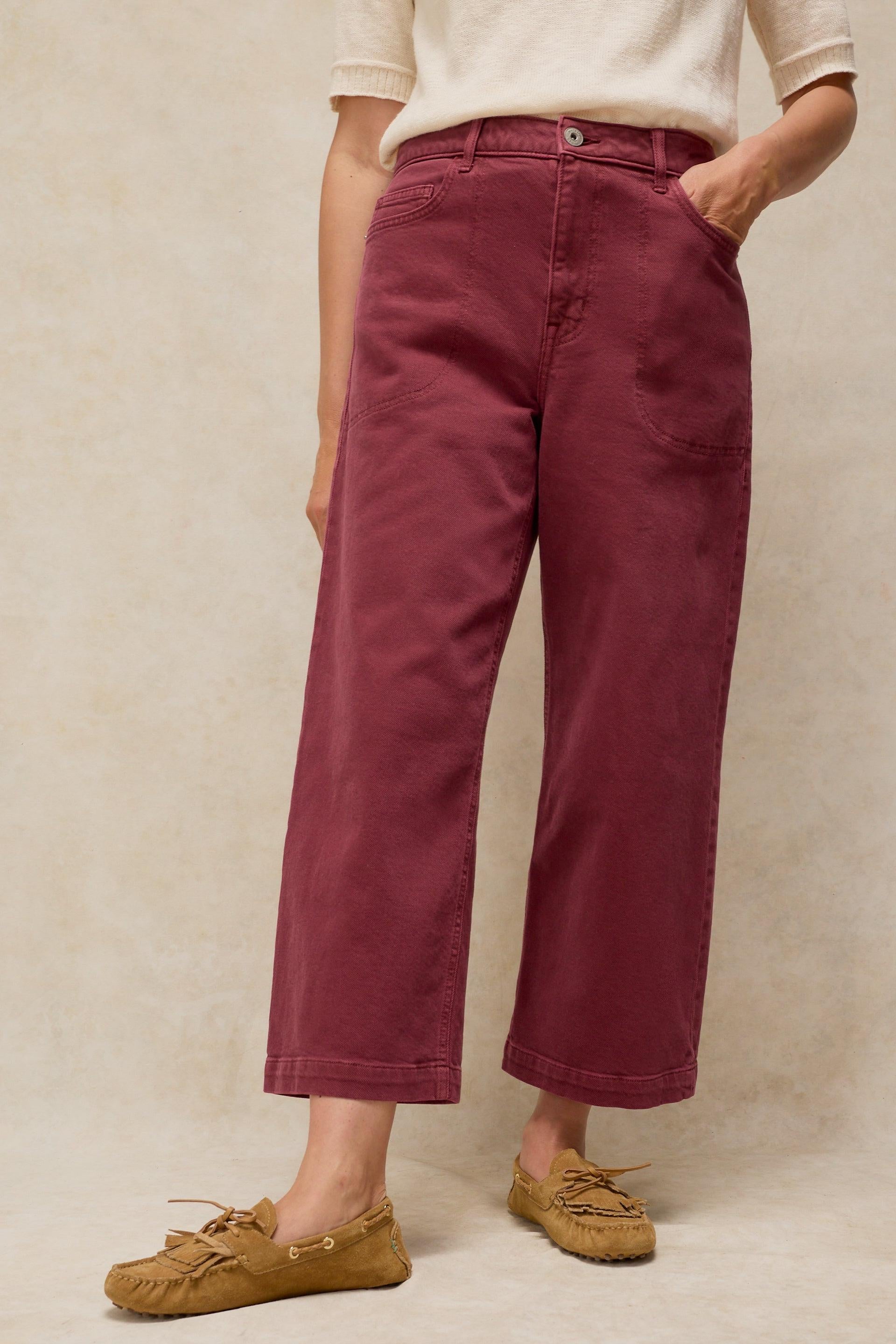 A woman wearing high-waisted burgundy trousers and a cream organic cotton top.