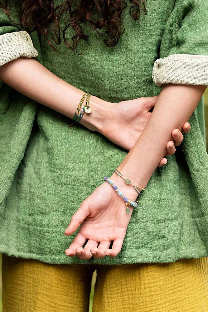 Woman wearing three different beaded bracelets with hands behind her back