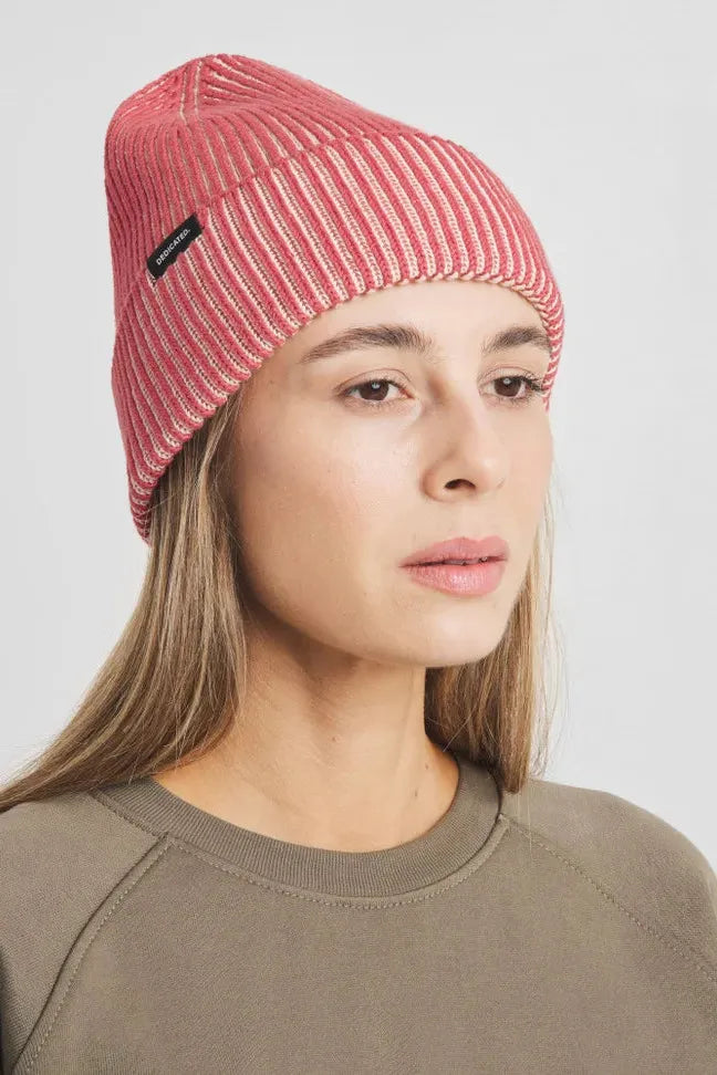 A woman wearing a ribbed red Dedicated Clothing cotton beanie hat against a plain white background.
