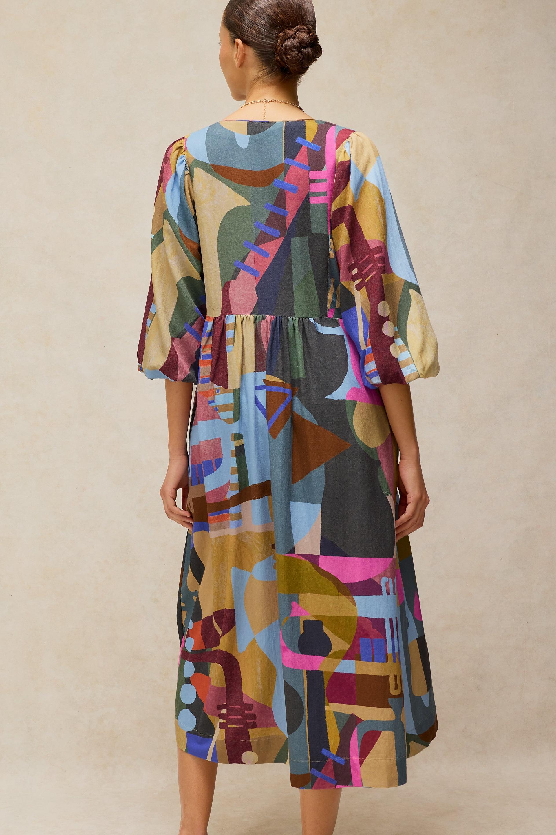 Woman wearing a colorful abstract print Ecovero midi dress, back view.