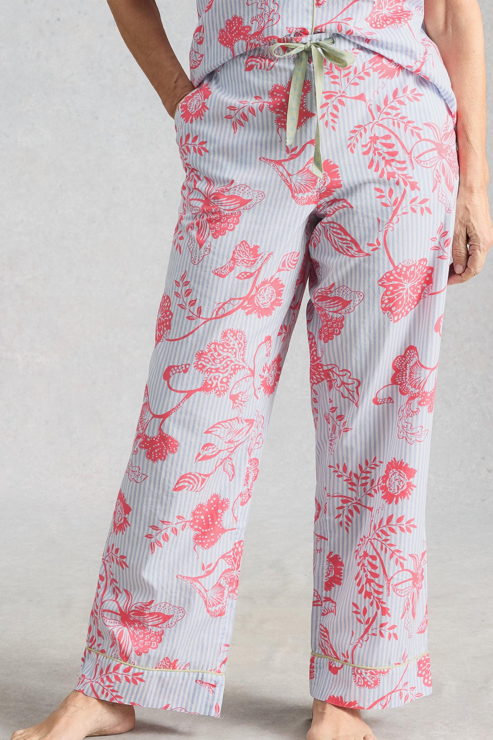 A person wearing blue and white striped organic cotton pyjamas with a pink floral pattern against a light grey background.