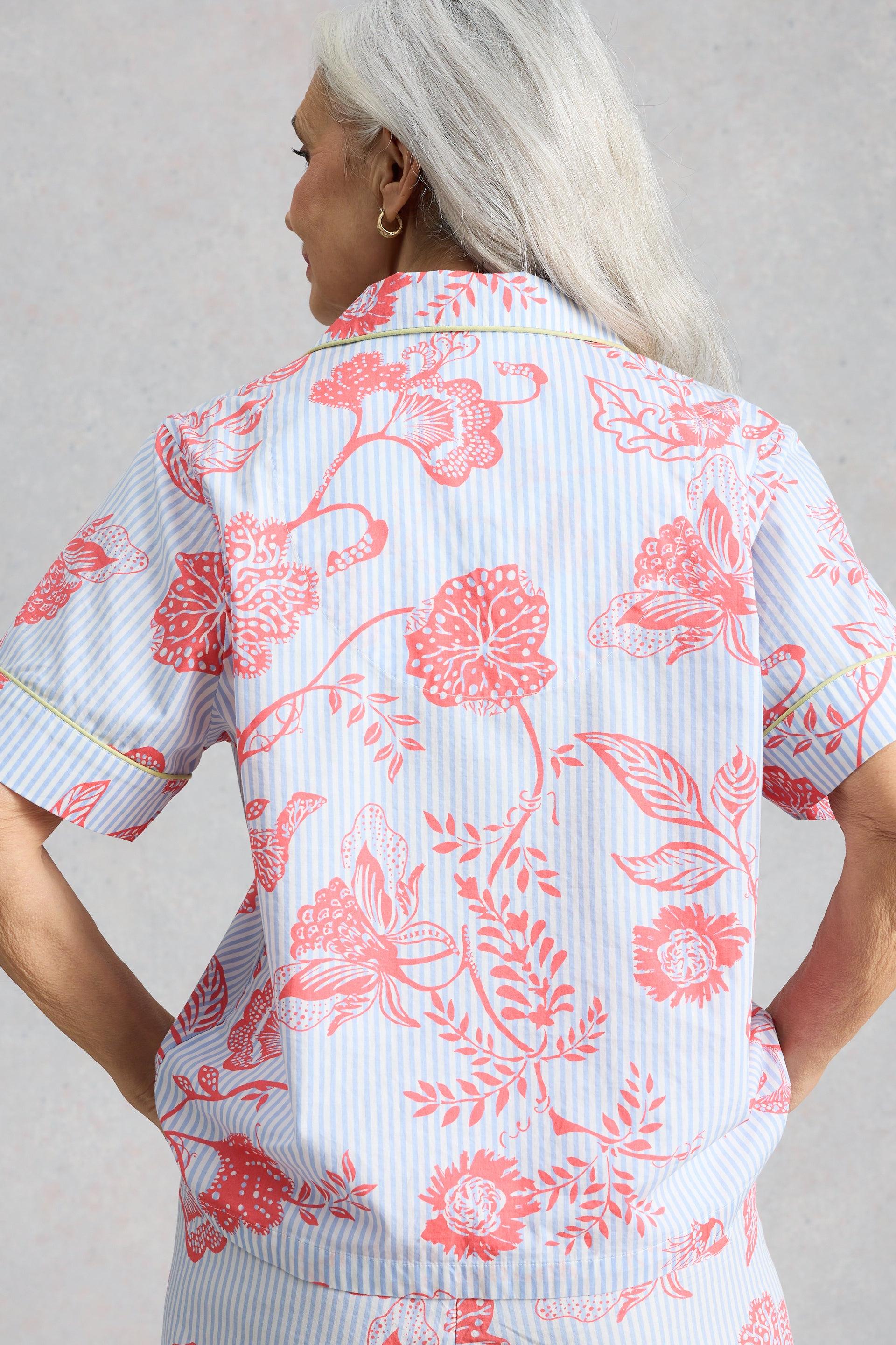 Woman seen from behind wearing light blue and pink floral organic cotton pyjamas.