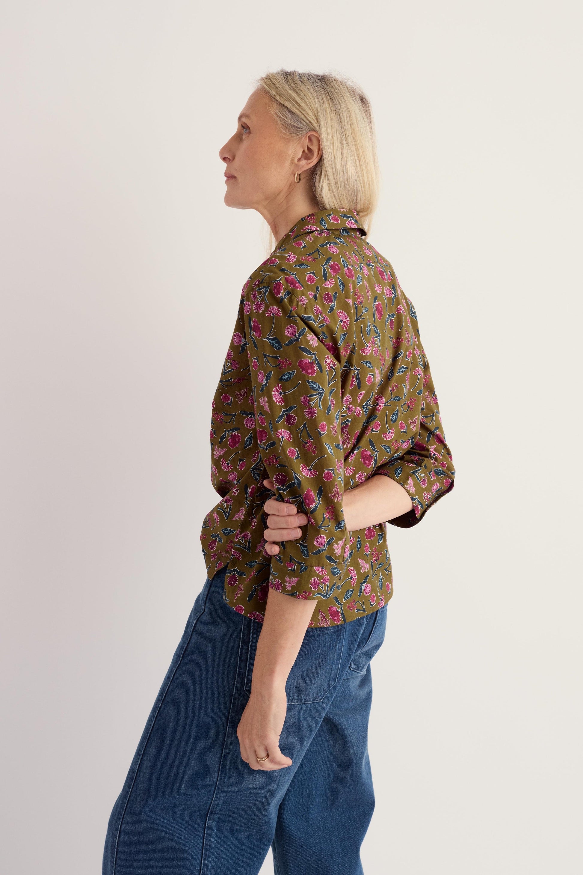 A woman wearing a green floral organic cotton top by Seasalt, shown from the side against a neutral background.