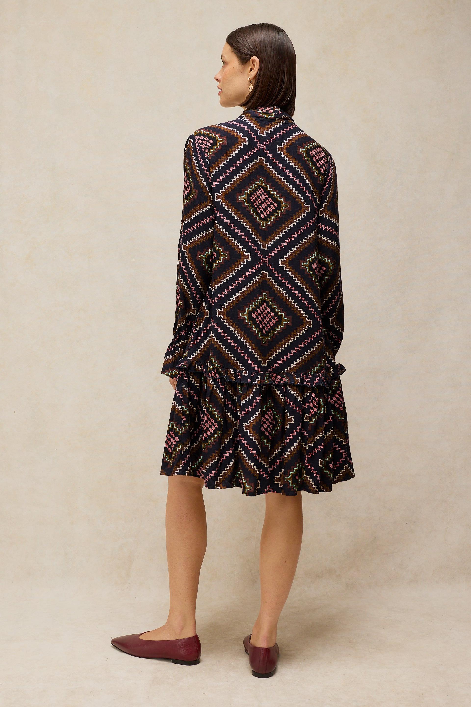 Woman wearing a patterned dress with a neutral background