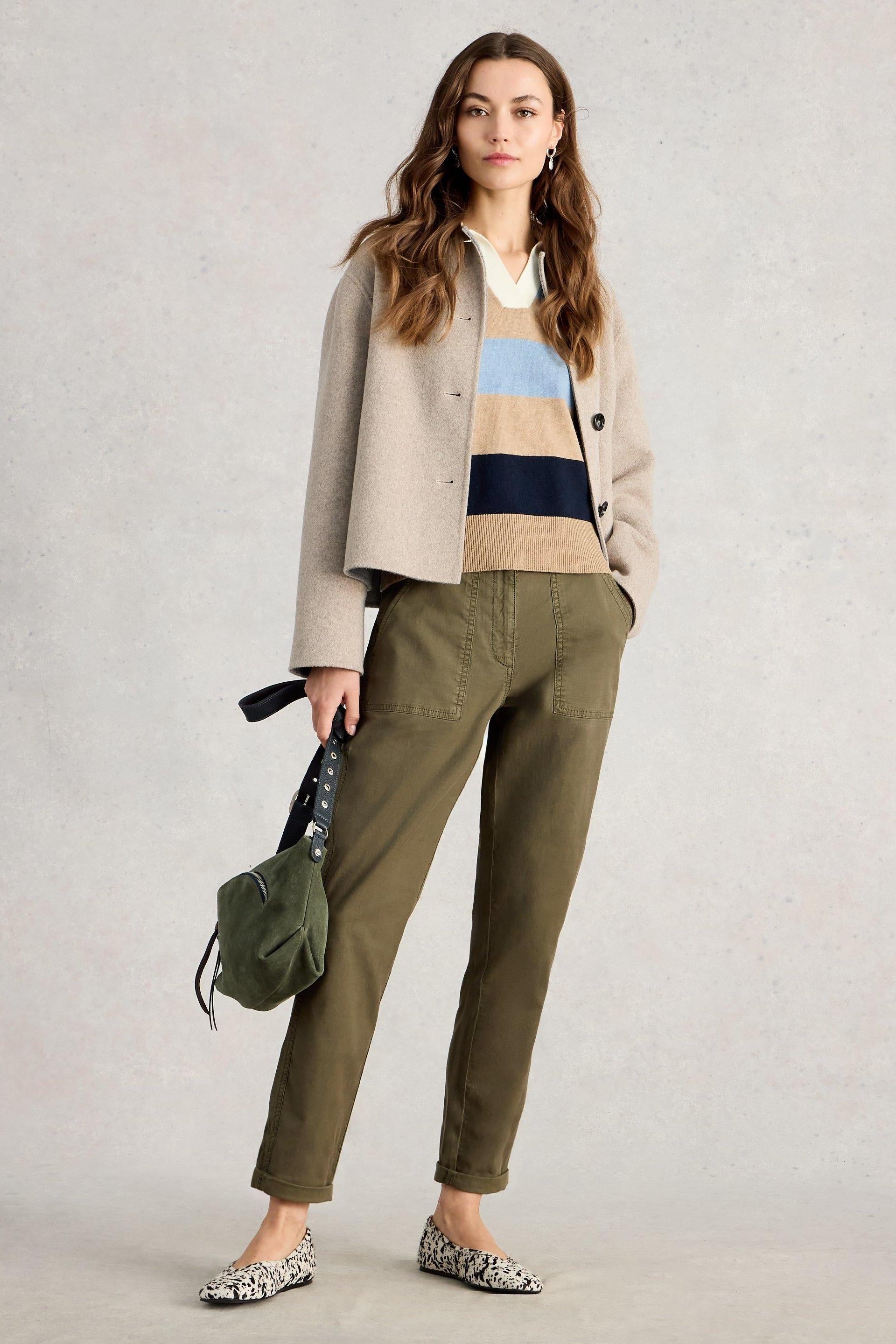 Woman posing in khaki White Stuff Twister chino trousers, striped sweater, and beige jacket.