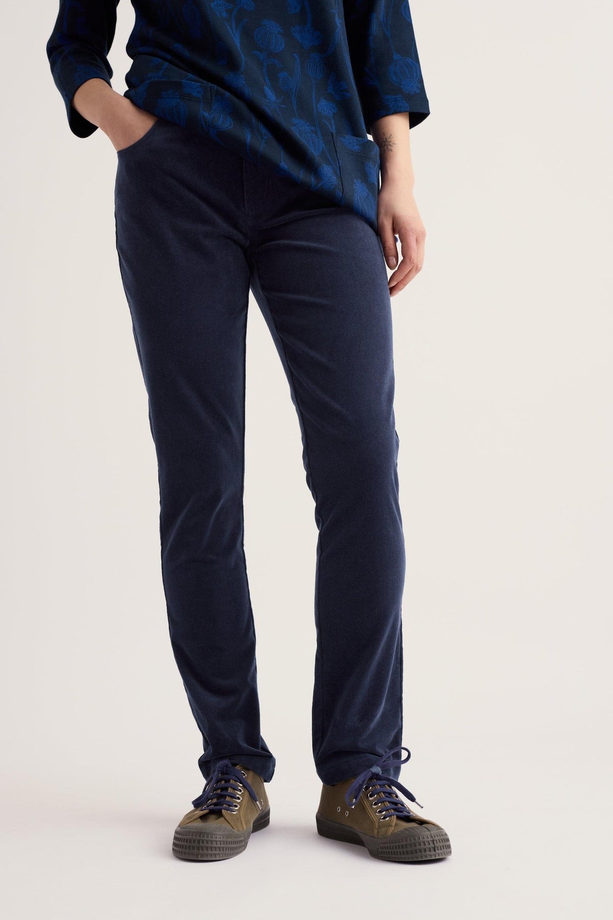 Woman modelling Seasalt Cornwall navy organic cotton cord trousers paired with olive green sneakers.