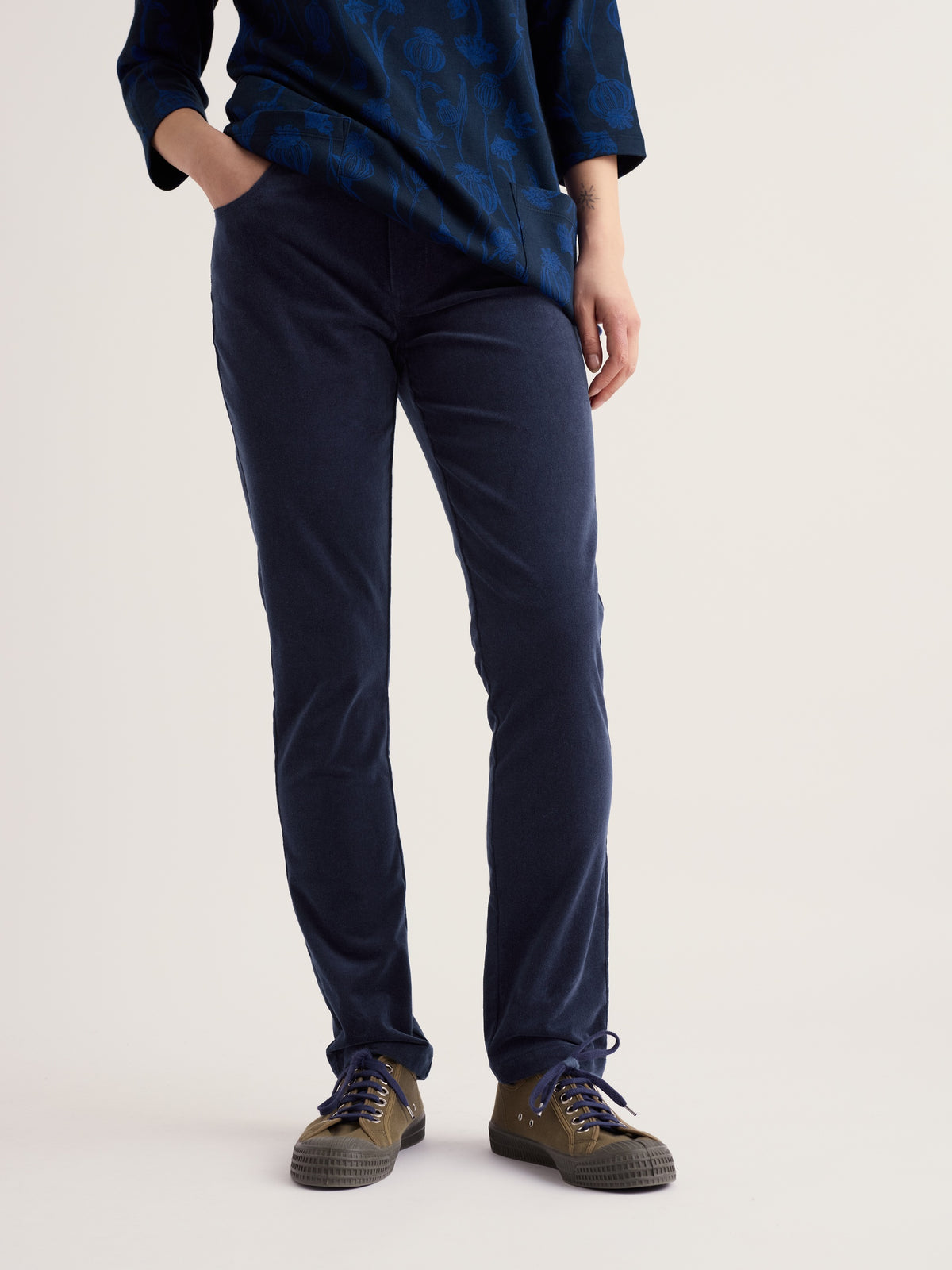 Woman modelling Seasalt Cornwall navy organic cotton cord trousers paired with olive green sneakers.