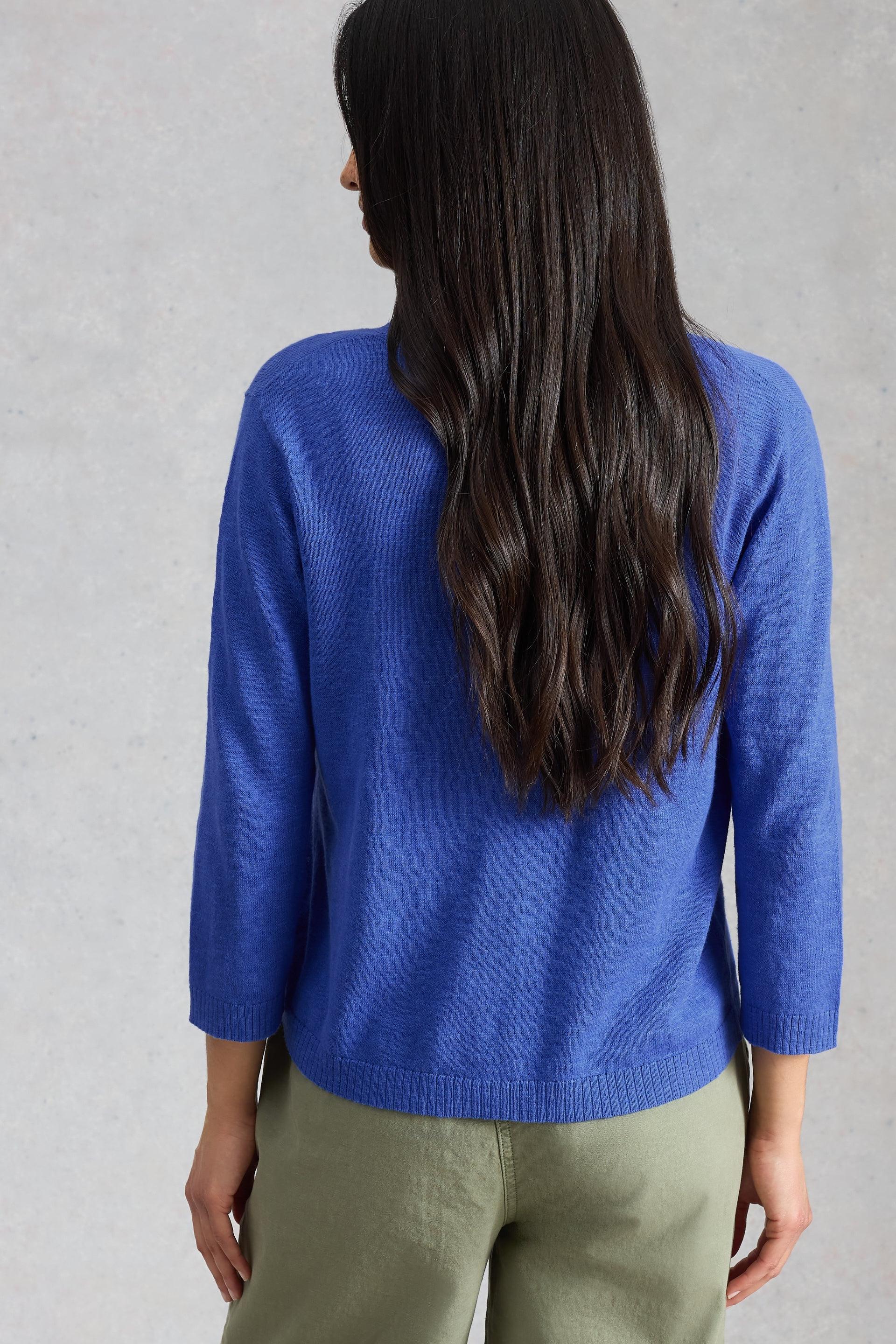 Woman seen from behind wearing a blue organic cotton cardigan.