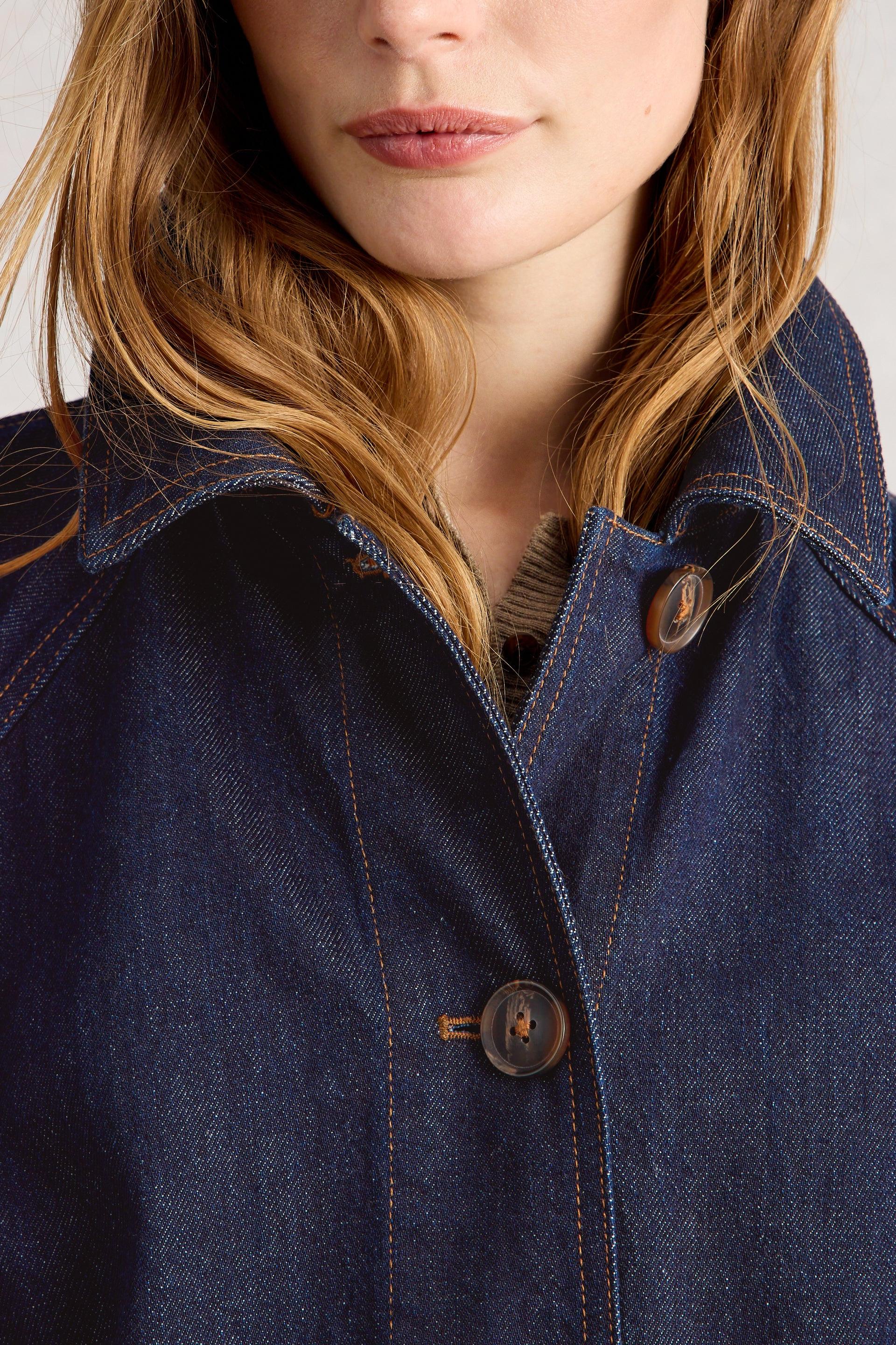 Close-up of a person wearing a blue organic cotton denim jacket with a neutral background
