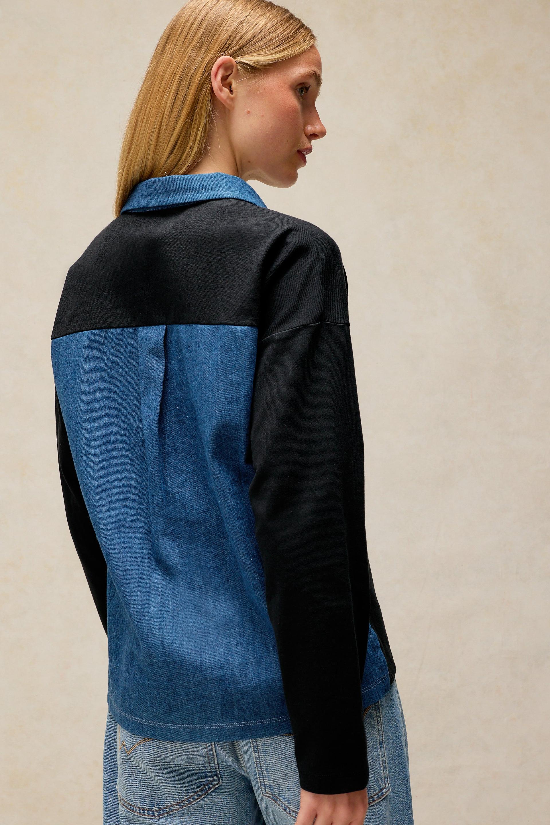 A woman wearing a stylish blue denim and black organic cotton shirt, seen from the back