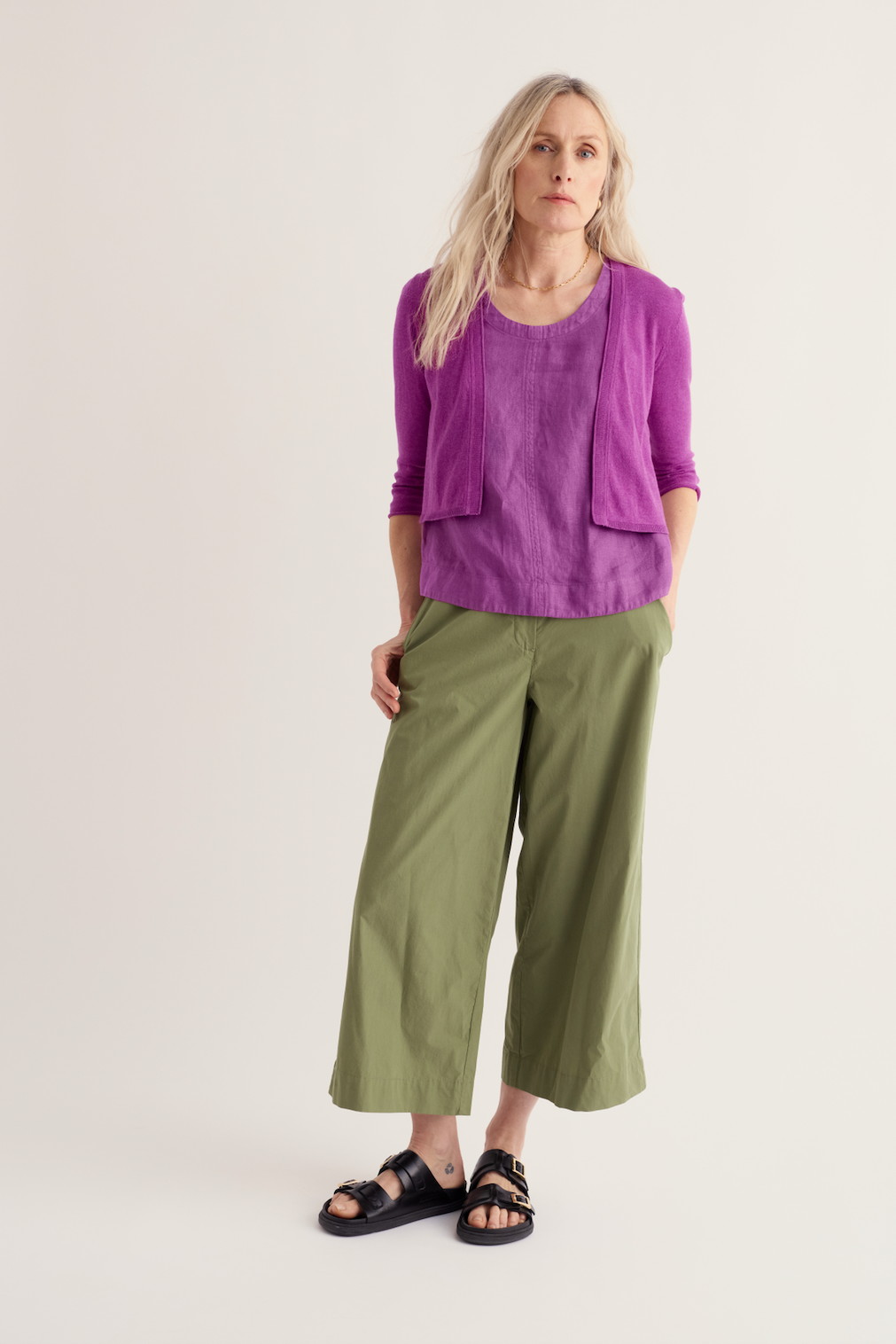 Woman wearing a purple organic cotton top and olive green trousers, representing sustainable fashion.