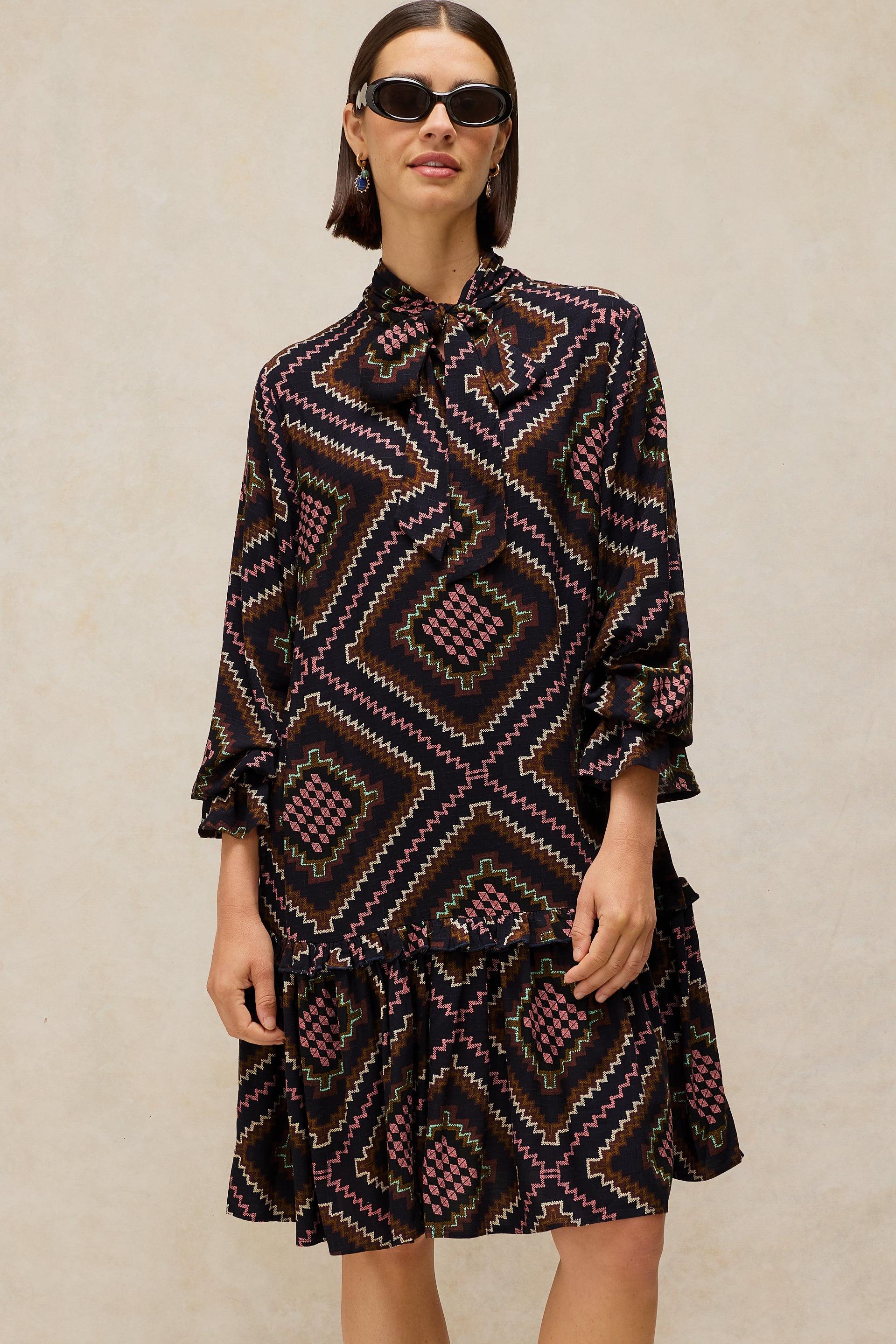 Woman wearing a patterned dress against a neutral background